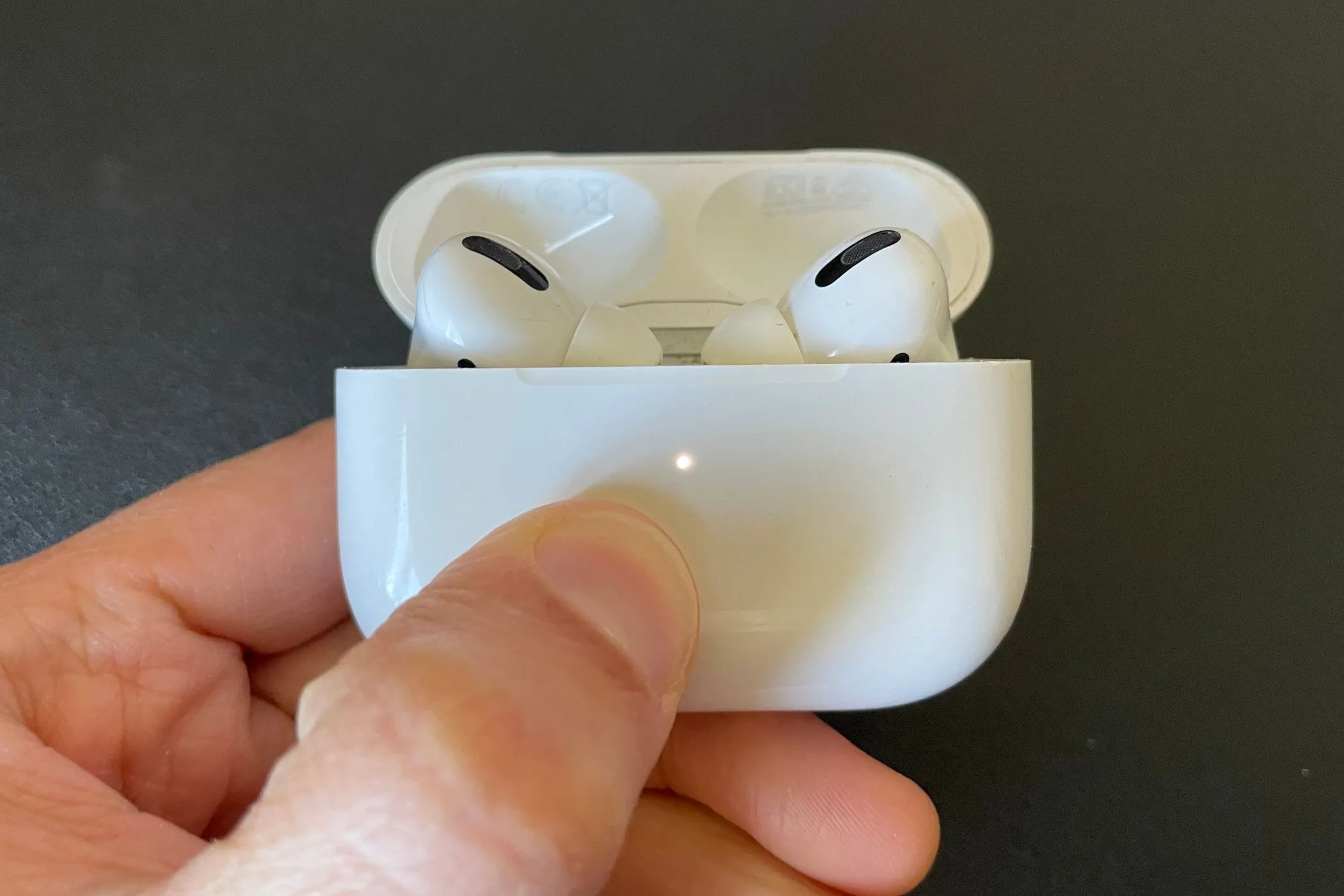AirPods Pro nằm trong hộp sạc đang sạc, biểu thị vấn đề về tuổi thọ pin không thể thay thế.