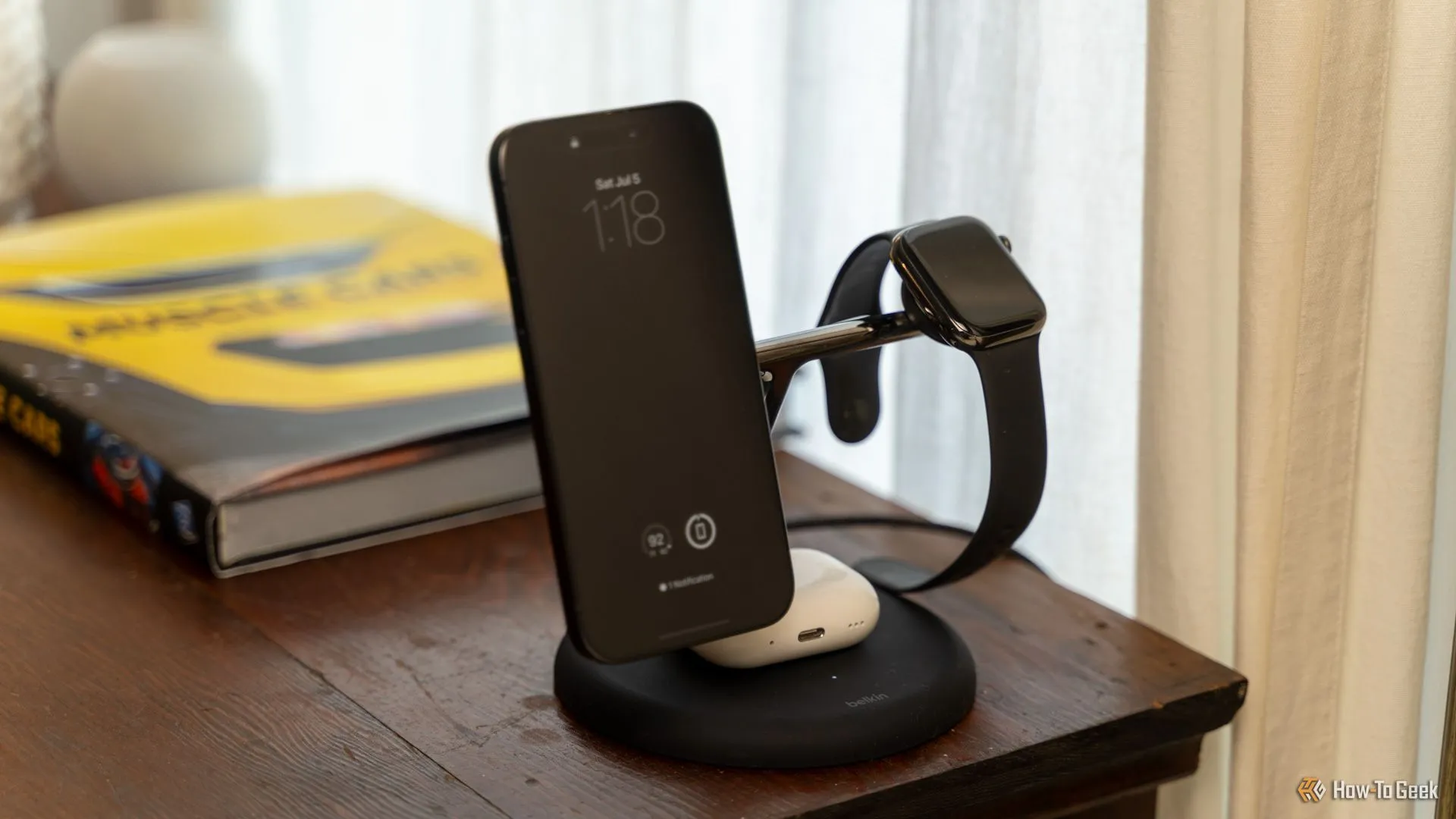 Bộ sạc Belkin BoostCharge Pro 3-in-1 MagSafe đang sạc cùng lúc iPhone, Apple Watch và AirPods trên bàn gỗ gọn gàng