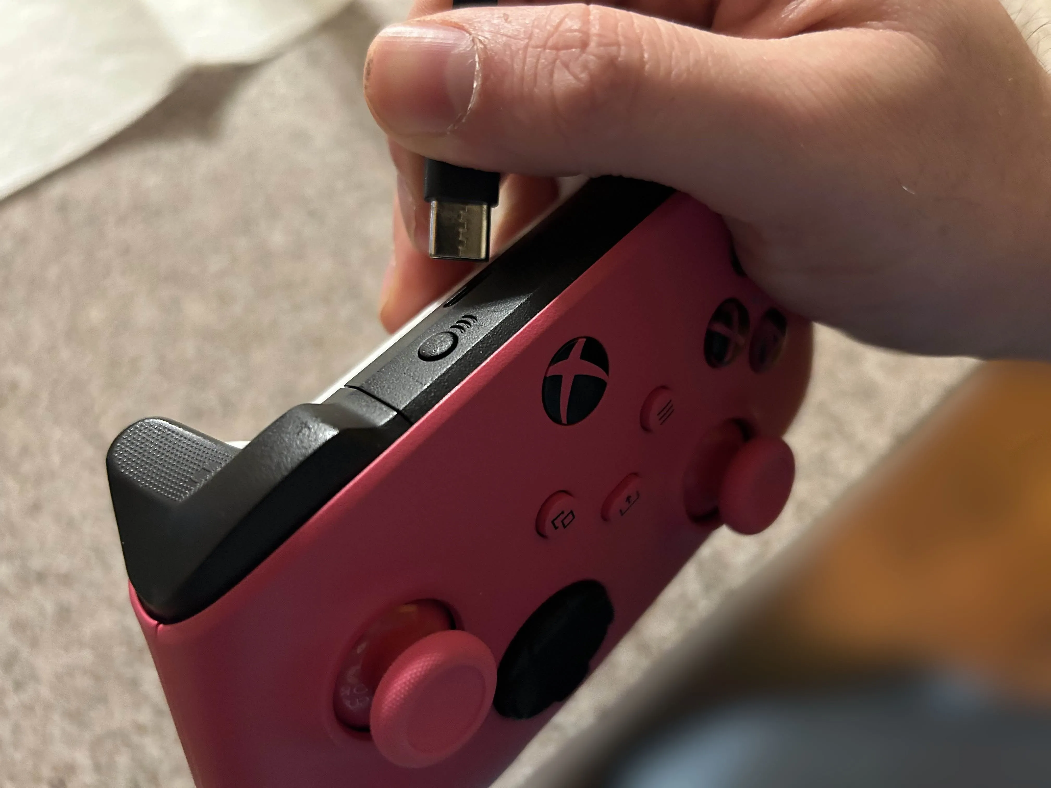 Cắm dây sạc vào cổng USB-C của tay cầm Xbox màu hồng, minh họa cho việc vệ sinh cổng kết nối.