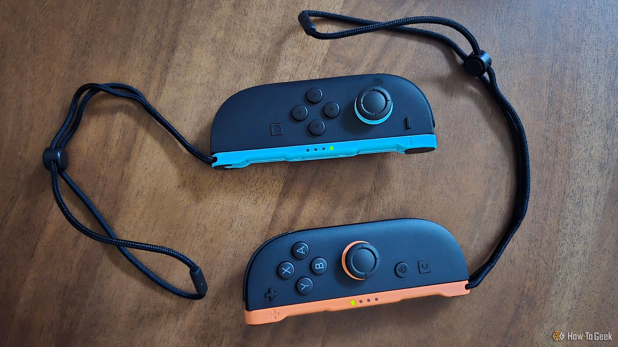 Cặp tay cầm Joy-Con 2 thế hệ mới kèm dây đeo cổ tay trên bàn.