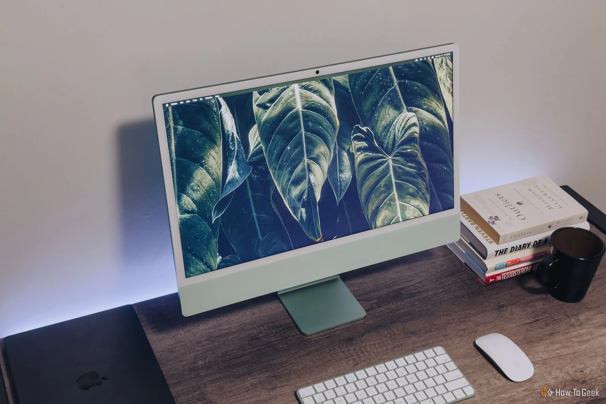 Màn hình iMac M4 màu xanh lá cây từ góc nhìn lên trên bàn gỗ