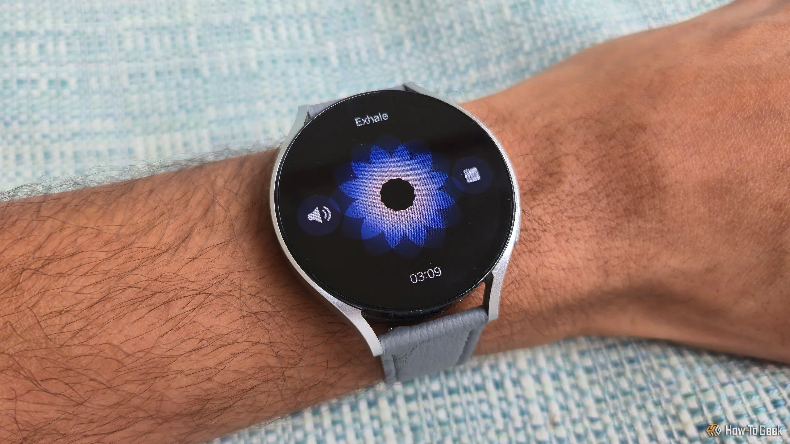 Màn hình ứng dụng tập thở trên Galaxy Watch 6, hiển thị hình ảnh hoa trừu tượng nở ra và co lại, hướng dẫn người dùng hít thở theo nhịp để giảm căng thẳng.