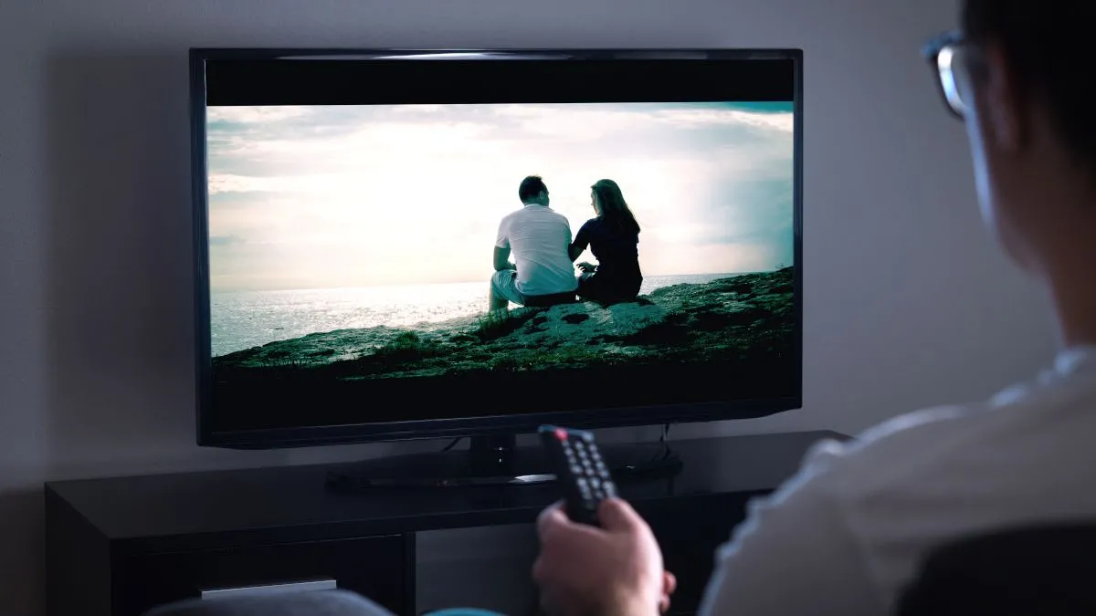 Người đàn ông dùng điều khiển từ xa chỉ vào TV, minh họa việc sử dụng TV OLED hàng ngày
