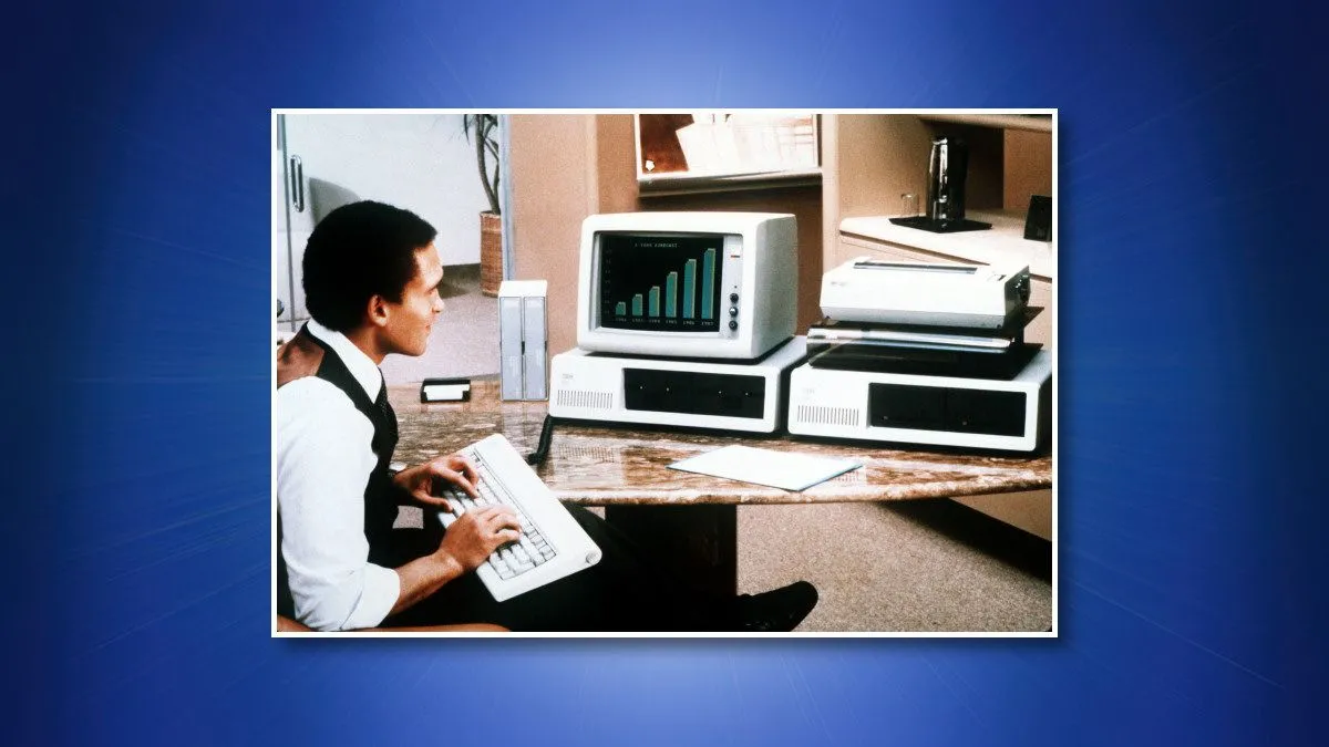 Người đàn ông sử dụng máy tính IBM PC 5150, đại diện cho hệ thống PC cạnh tranh với Macintosh II