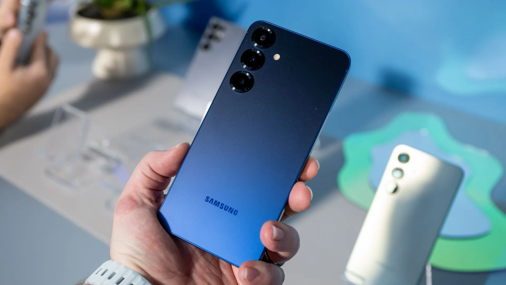 Người dùng cầm Samsung Galaxy S25 màu Navy Blue, nổi bật với hệ thống ba camera sau.