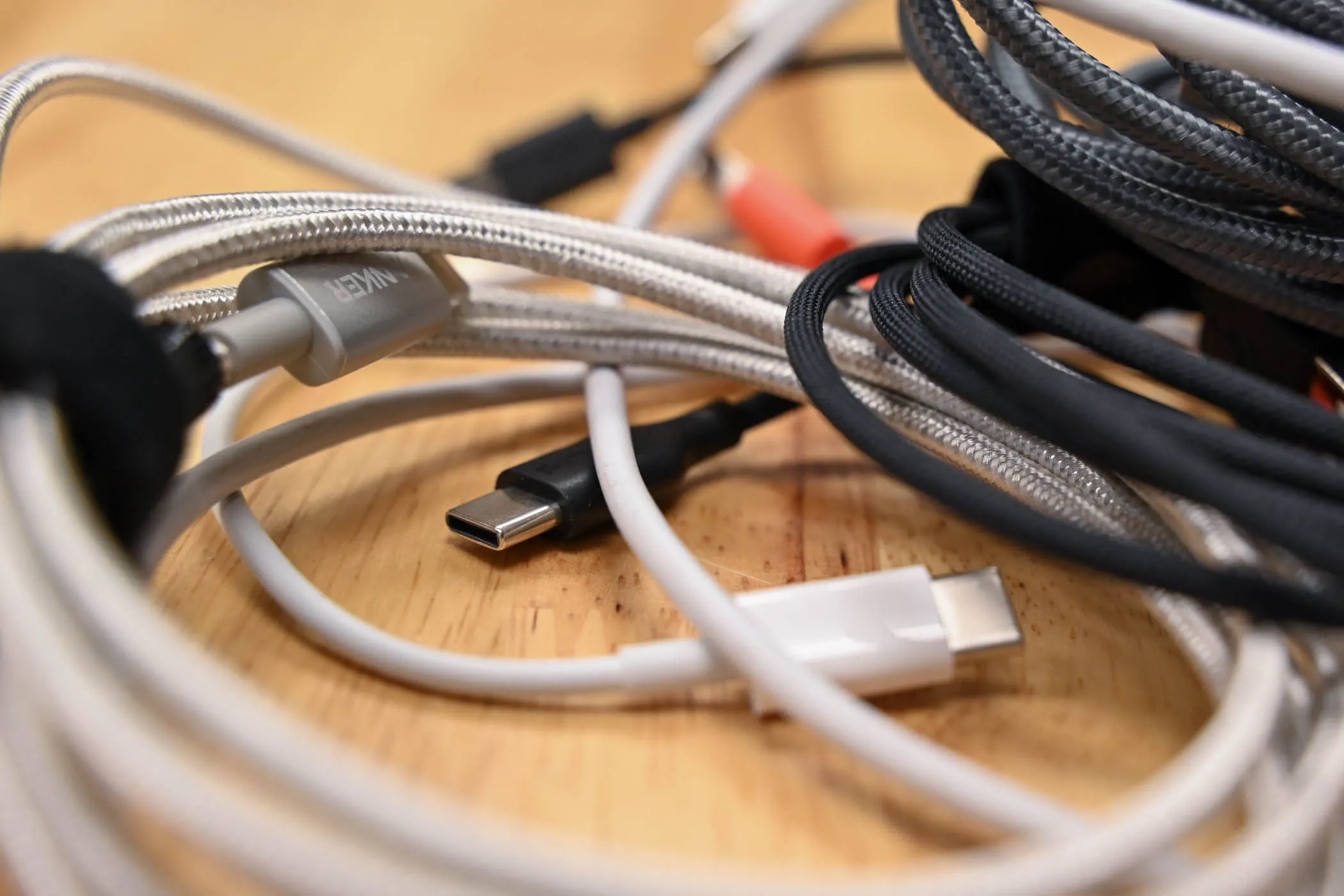 Nhiều loại cáp USB đặt trên nền gỗ, minh họa sự đa dạng của chuẩn kết nối này.