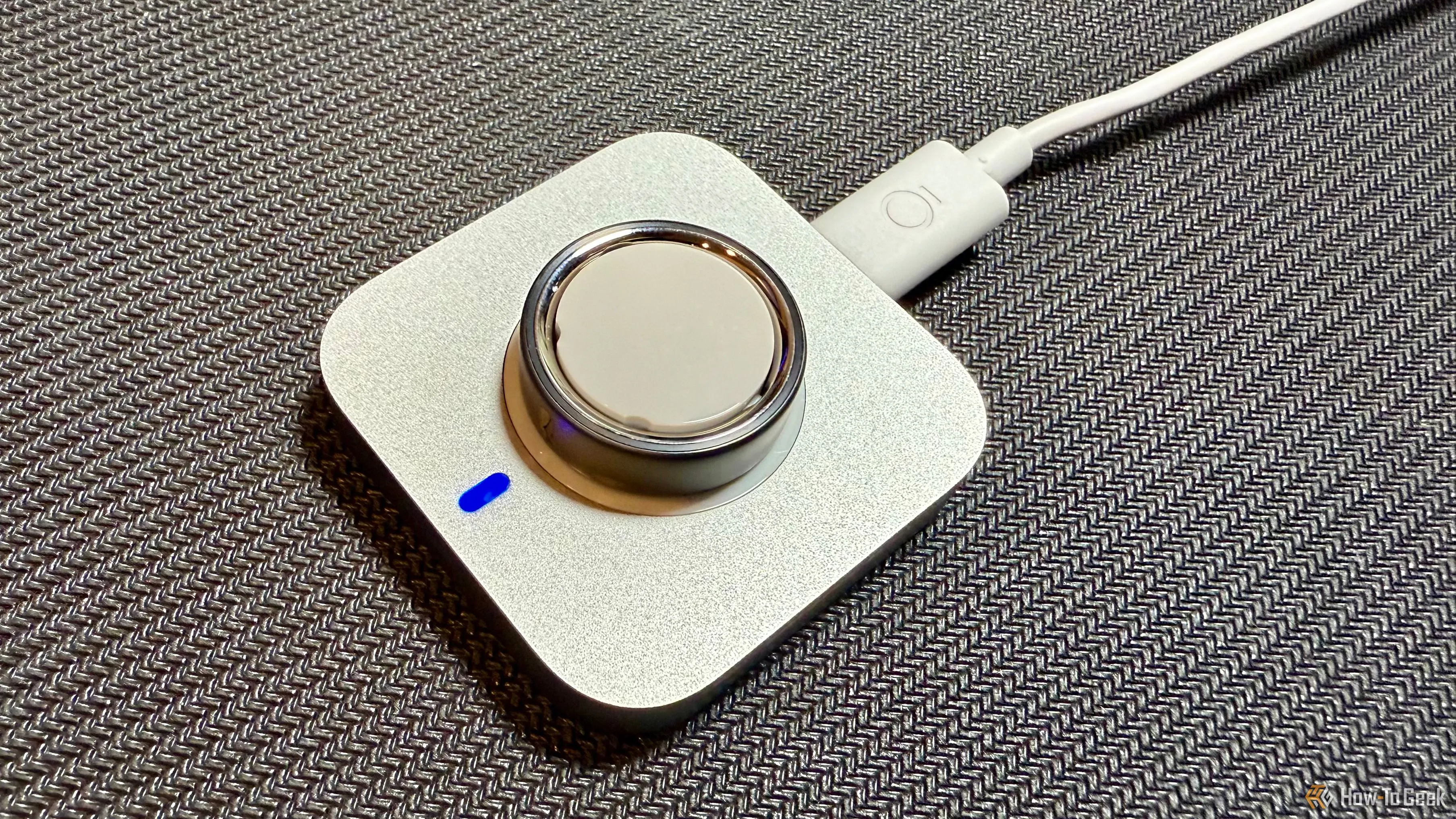 Oura Ring 4 đang được sạc trên đế sạc của nó