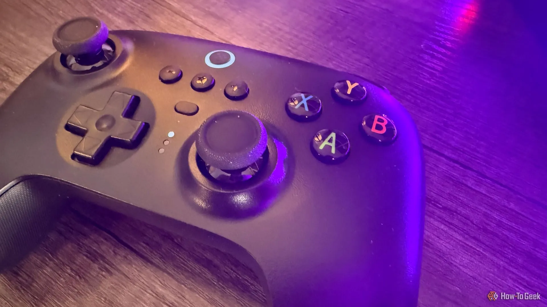 Tay cầm chơi game 8BitDo Ultimate 2.4G hiện đại đặt trên bàn với ánh sáng tím, minh họa khả năng tái sử dụng tay cầm game cũ với PC cho trải nghiệm chơi game mượt mà.