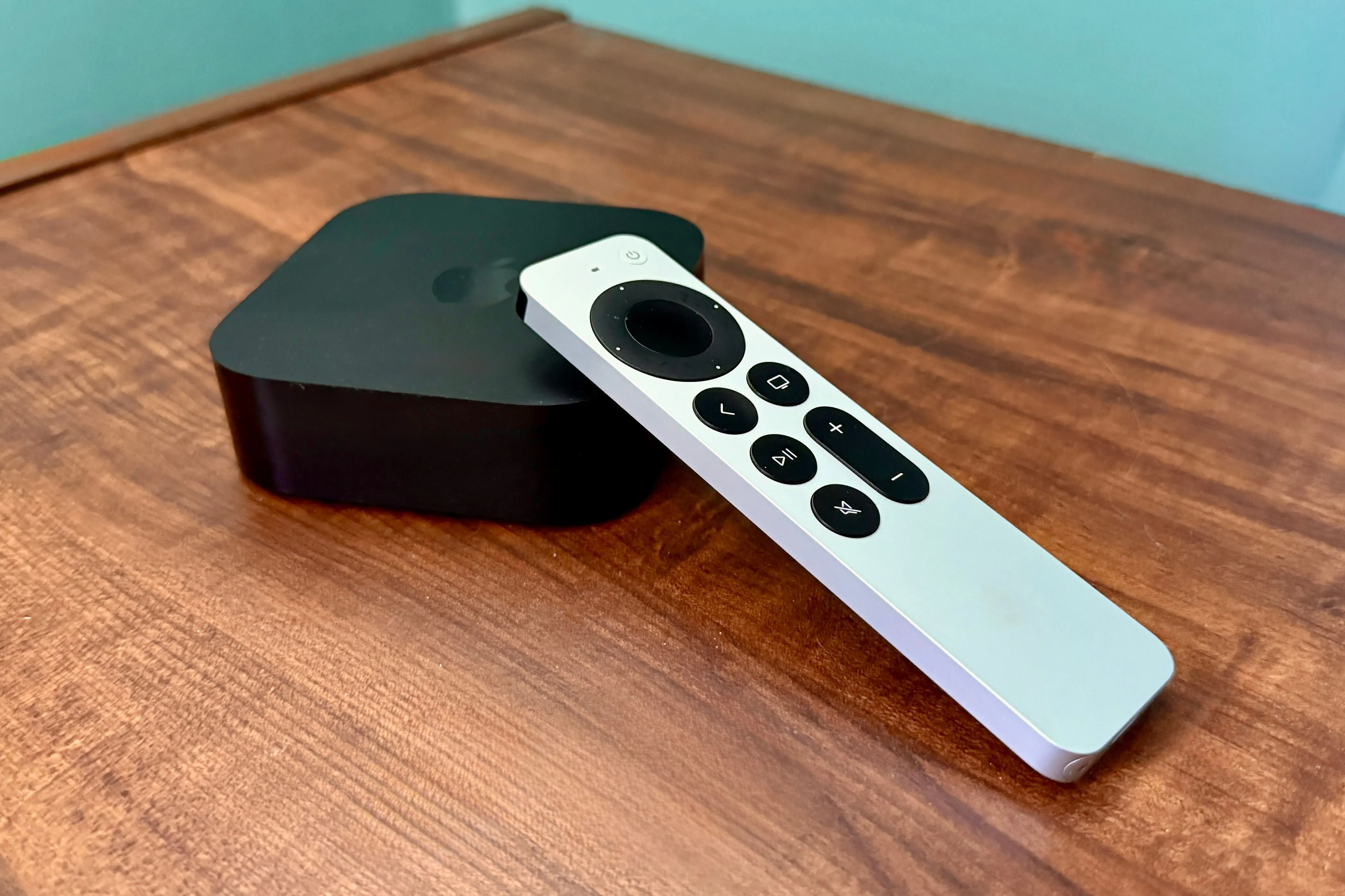 Thiết bị Apple TV 4K và điều khiển từ xa đặt trên bàn gỗ, minh họa giao diện tvOS thân thiện và tích hợp hệ sinh thái Apple.