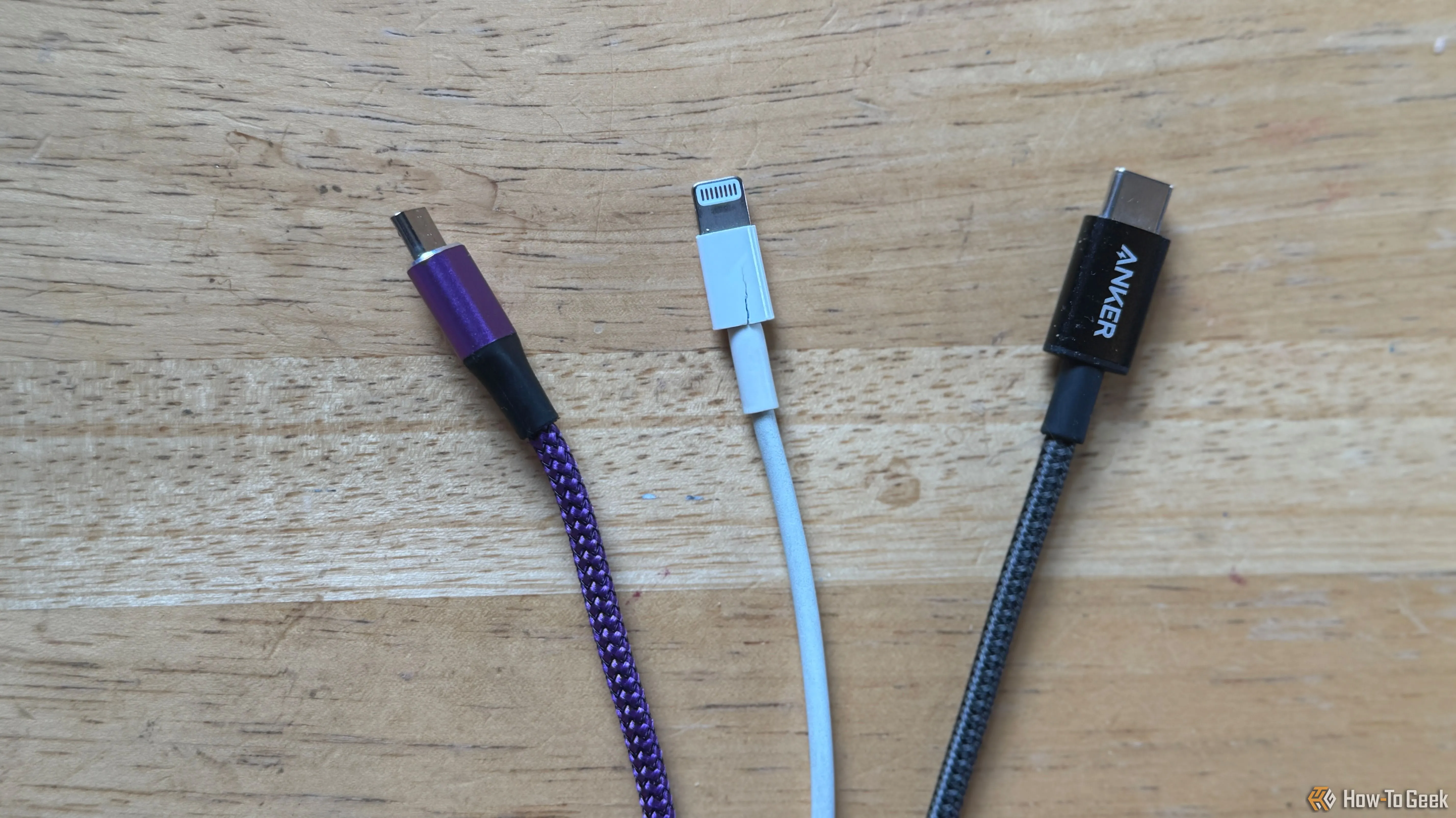 Ba sợi cáp sạc màu sắc khác nhau gồm cáp micro-USB màu tím, cáp Lightning màu trắng và cáp USB-C màu xám được đặt gọn gàng trên bàn, cho thấy lợi ích của việc phân biệt bằng màu sắc.