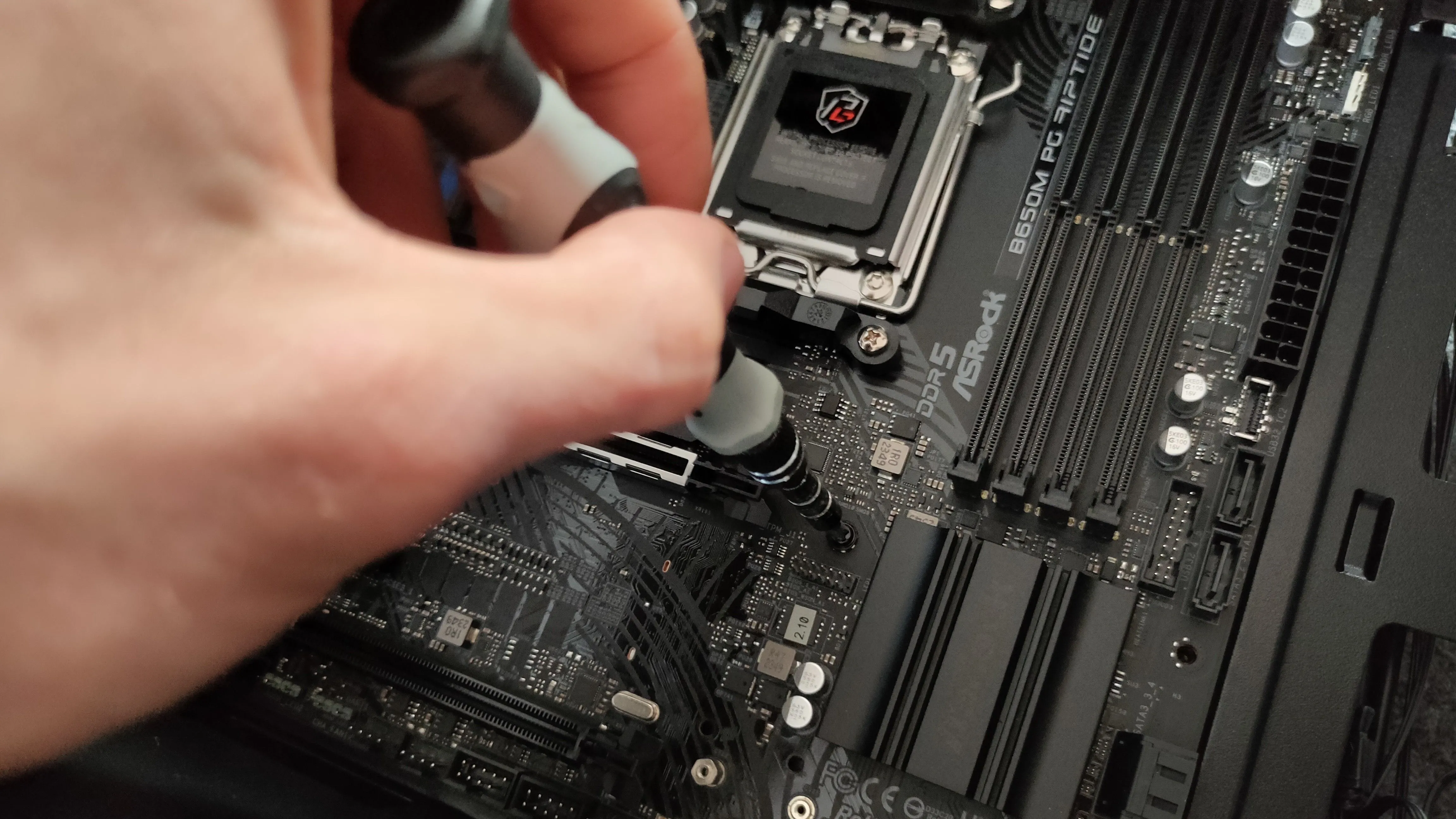 Bàn tay đang lắp đặt bo mạch chủ vào vỏ case PC, thể hiện công đoạn quan trọng trong quá trình xây dựng máy tính.