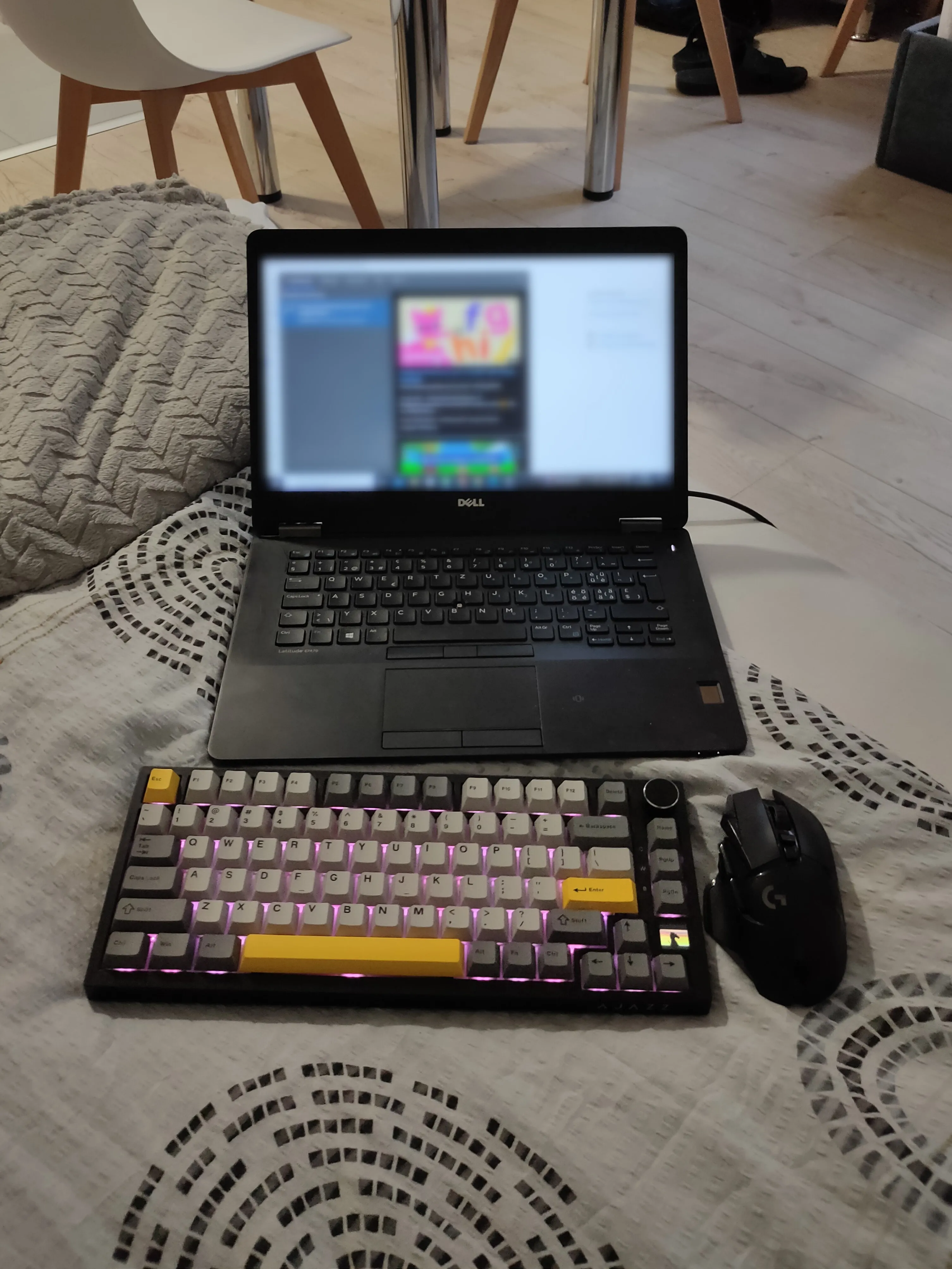 Bộ bàn phím không dây và chuột gaming đặt cạnh laptop trên giường, tạo tư thế thoải mái hơn khi chơi game.