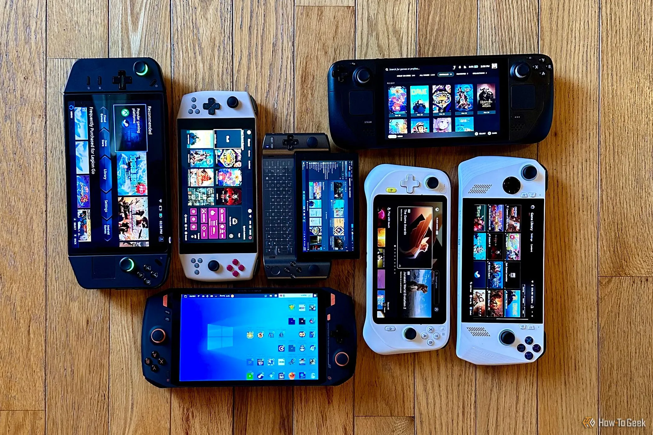 Bộ sưu tập các máy chơi game cầm tay PC phổ biến như Lenovo Legion Go, AYANEO 2021 Pro, Valve Steam Deck, GPD Win3, Logitech G Cloud, Asus ROG Ally và OneXPlayer 1 sắp xếp trên sàn, thể hiện sự đa dạng của thị trường handheld.