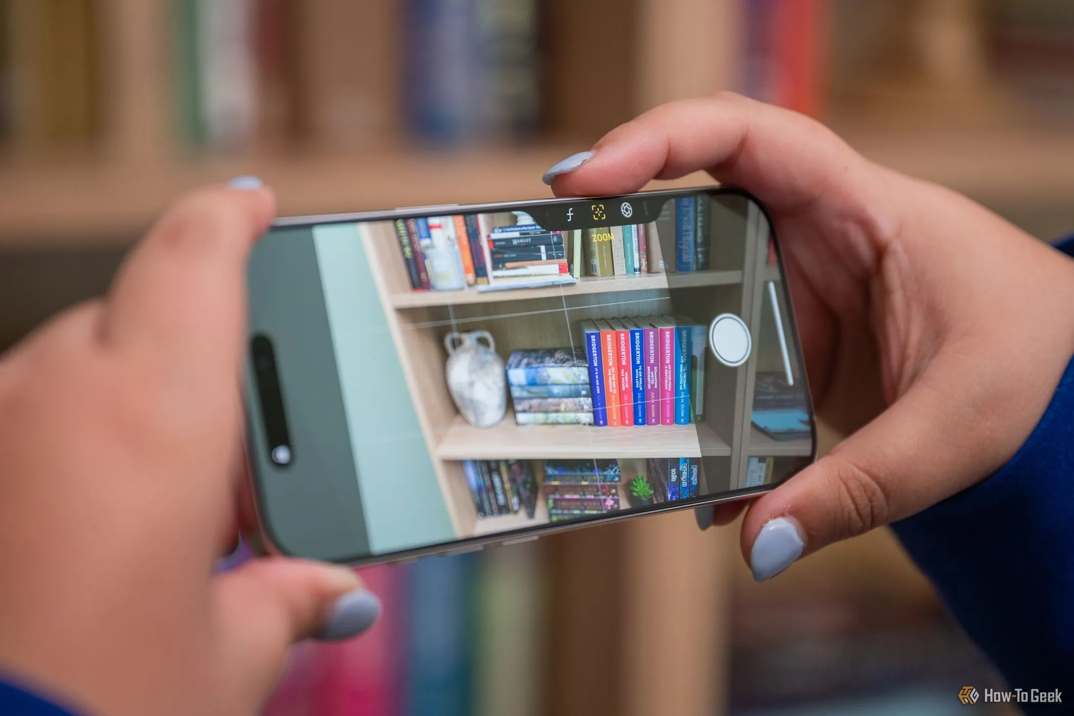 Chụp ảnh phong cảnh với iPhone 16 Pro, người dùng đang nhấn nút Camera Control để điều khiển camera ở chế độ ngang.