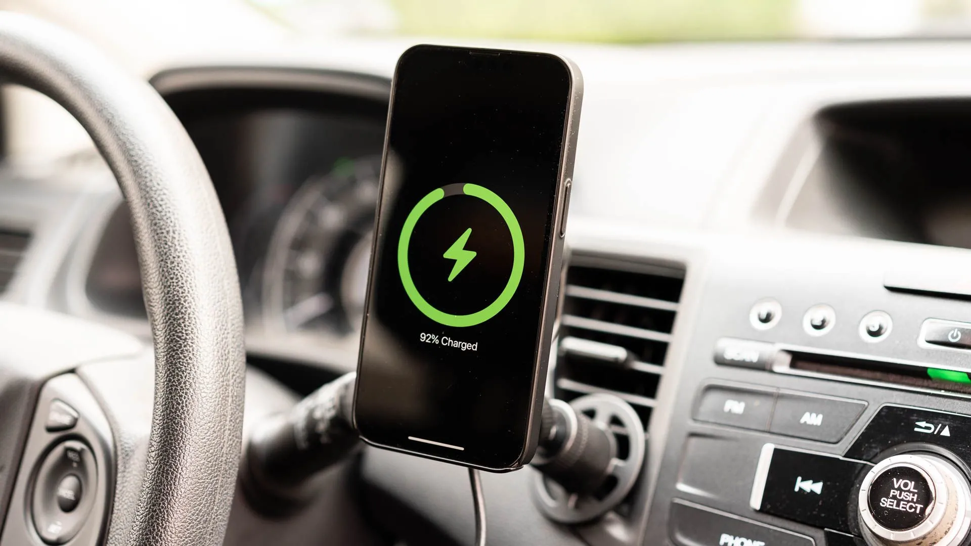 Điện thoại iPhone đang sạc trên giá đỡ sạc không dây mophie gắn cửa gió điều hòa với MagSafe, phụ kiện ô tô tiện lợi cho chuyến đi.