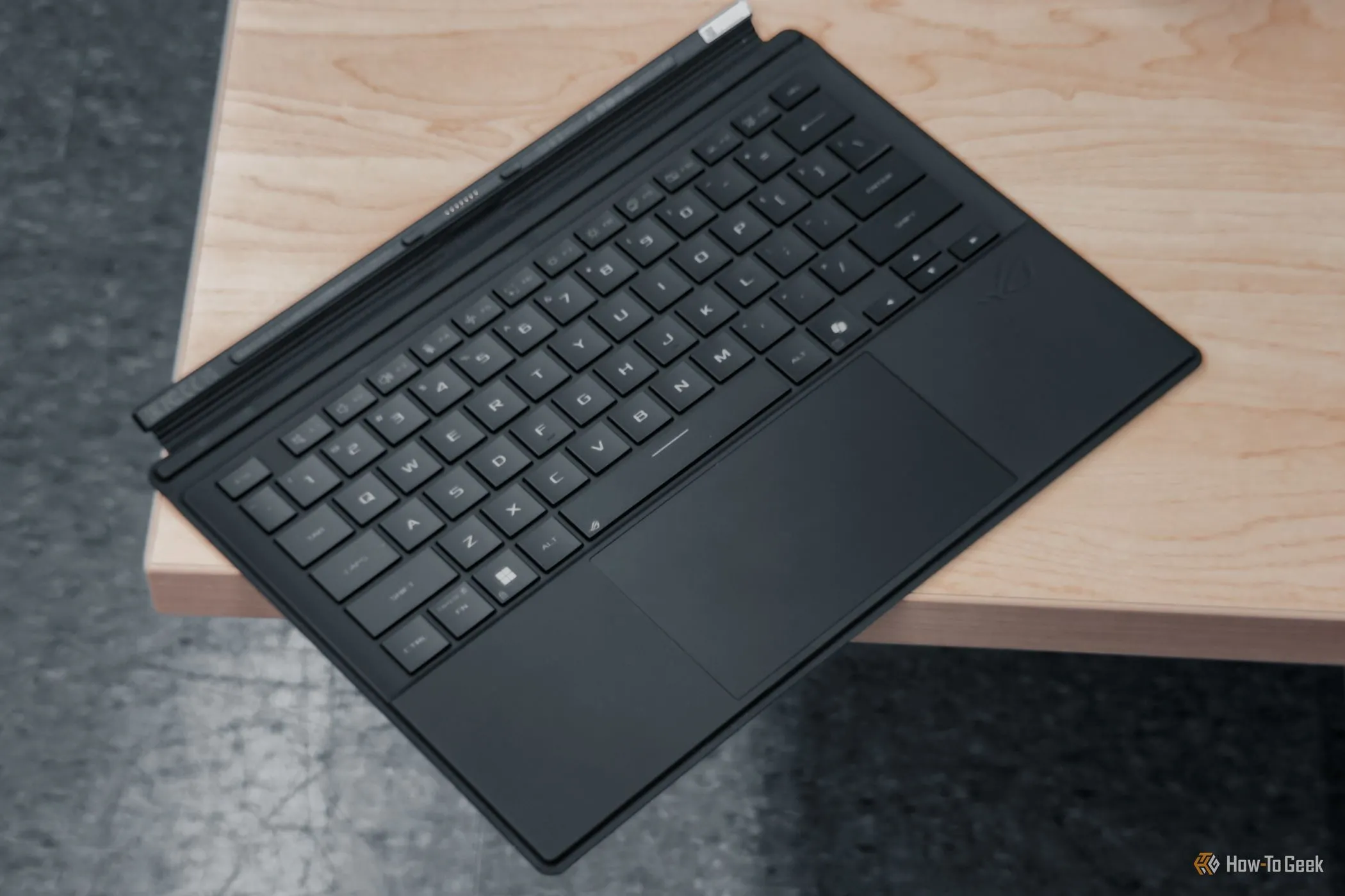 Góc nhìn nghiêng của bàn phím ASUS ROG Flow Z13 trên bàn, minh họa trackpad rộng rãi và thiết kế tổng thể