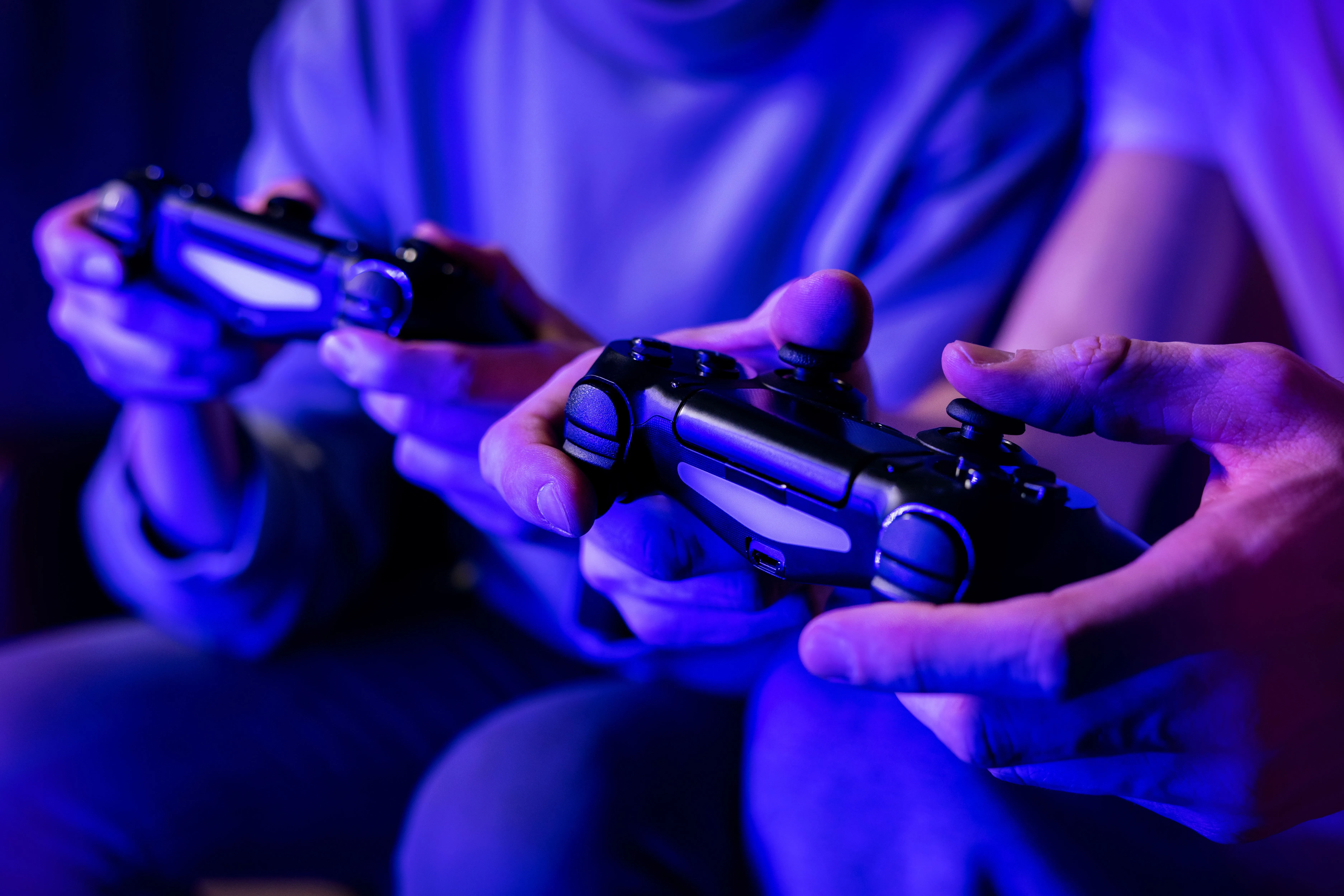 Hai người bạn chơi game multiplayer trên ghế sofa, mỗi người cầm tay cầm điều khiển, minh họa trải nghiệm điều khiển game.