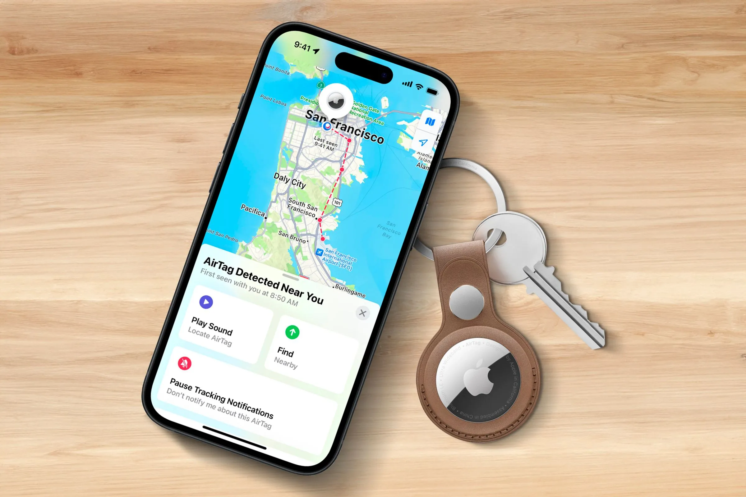 iPhone hiển thị vị trí AirTag trên bản đồ, với AirTag gắn chìa khóa đặt cạnh trên bề mặt gỗ, minh họa tính năng tìm kiếm.