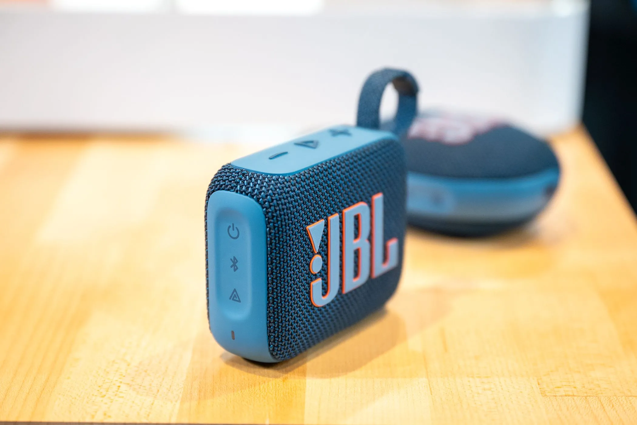 Loa Bluetooth di động JBL Go 4 màu xanh dương đặt trên bàn, phía trước là JBL Clip 5, lựa chọn tuyệt vời để chia sẻ âm nhạc khi đi du lịch.