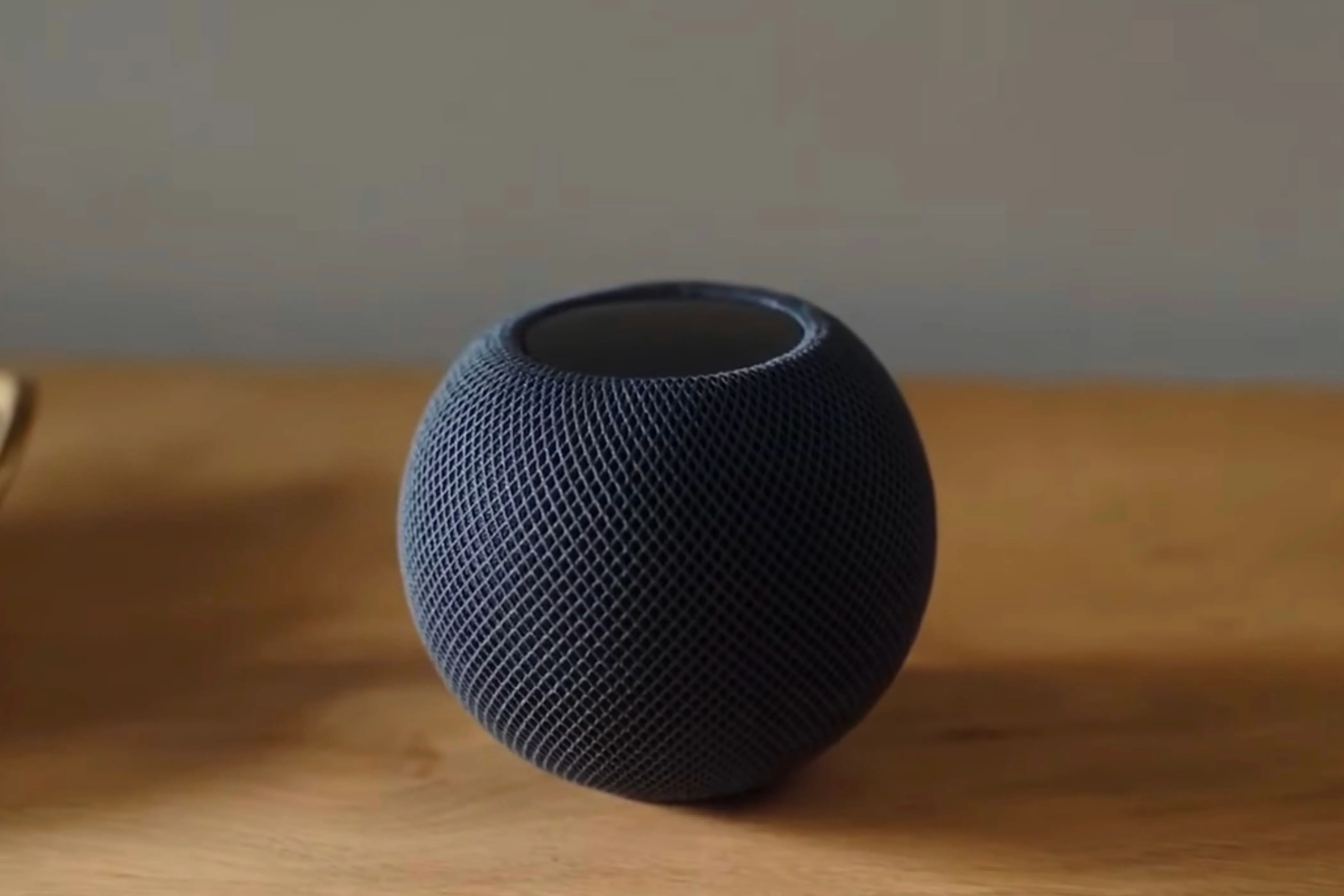 Loa HomePod Mini màu đen đặt trên bàn gỗ, minh họa cho việc điều khiển bằng Phím tắt Apple.