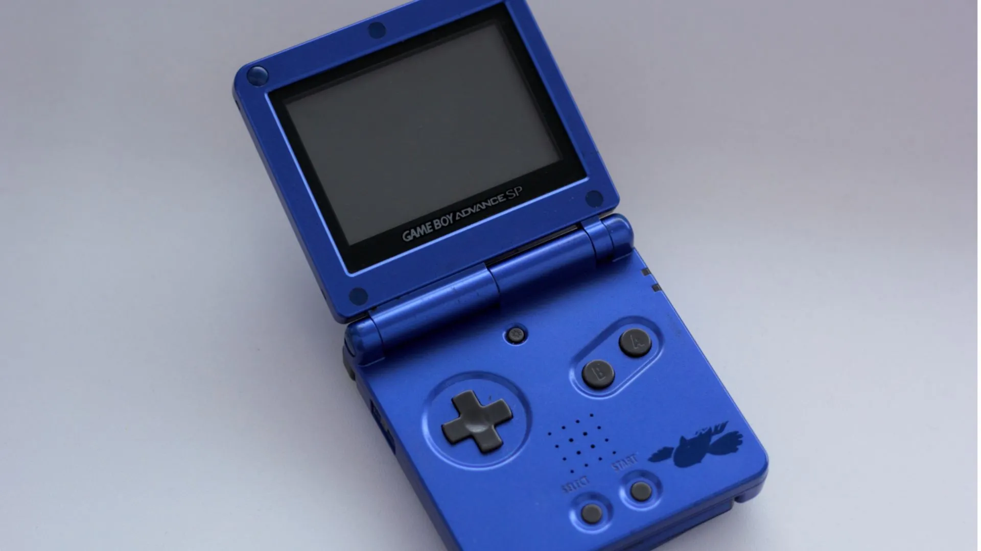 Máy chơi game Game Boy Advance SP với thiết kế gập vỏ sò và màn hình có đèn nền.