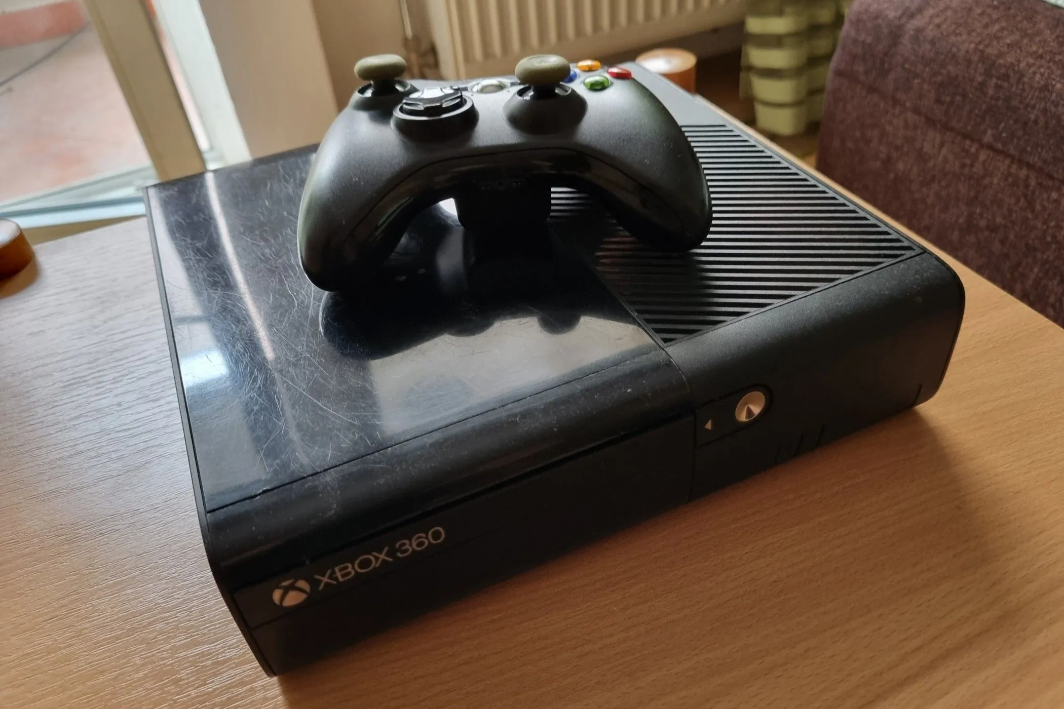 Máy Xbox 360 cũ cùng với tay cầm đặt bên trên