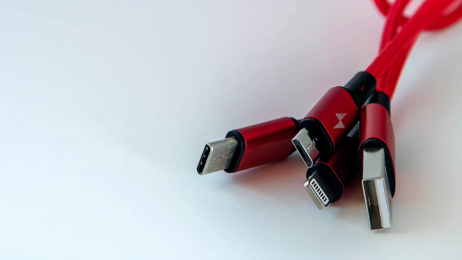 Một bó cáp sạc USB-C, Lightning và Micro-USB giá rẻ bị lộn xộn trên bàn, minh họa sự đa dạng và phức tạp của các loại dây sạc hiện nay.