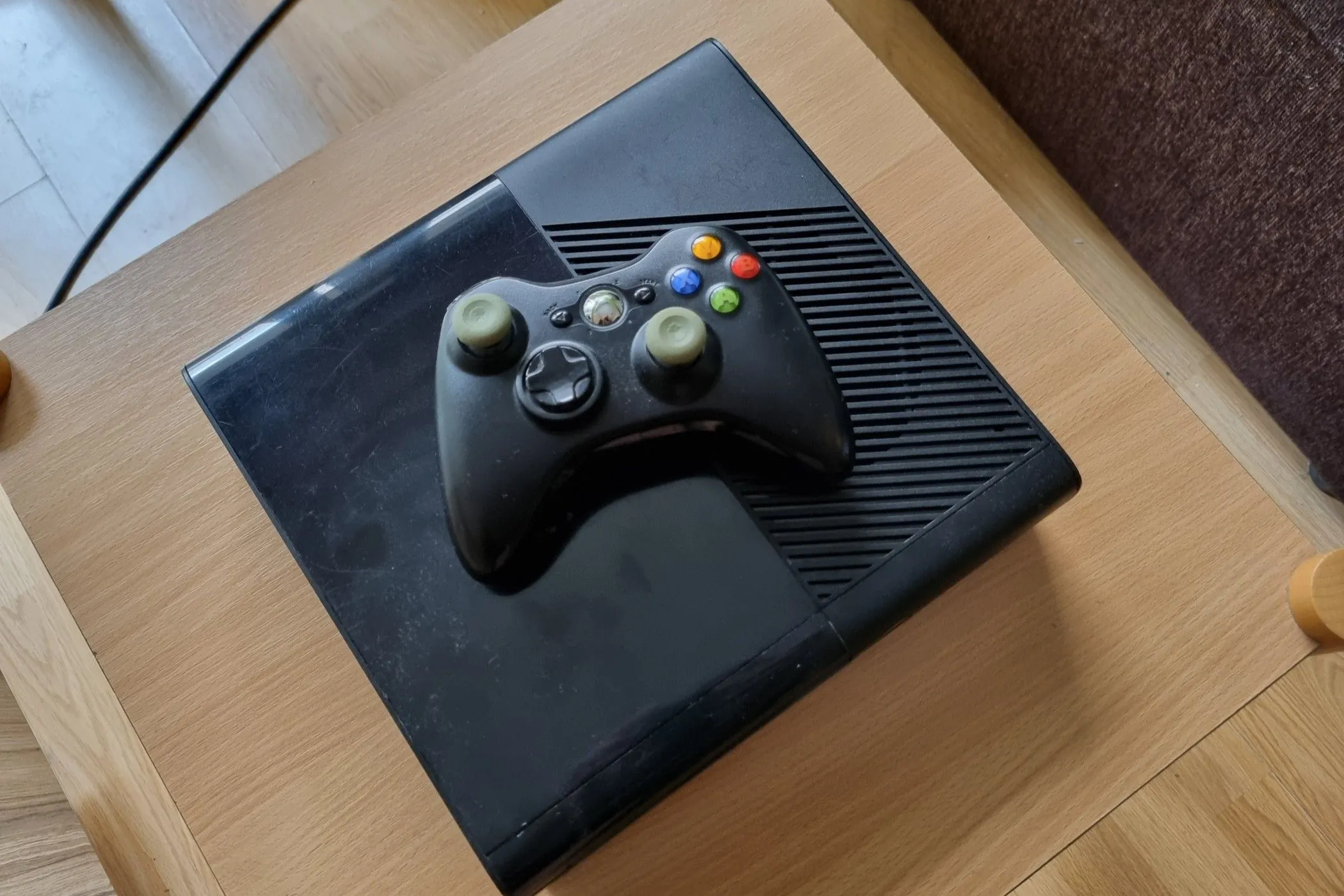 Một chiếc Xbox 360 cũ với tay cầm đặt phía trên