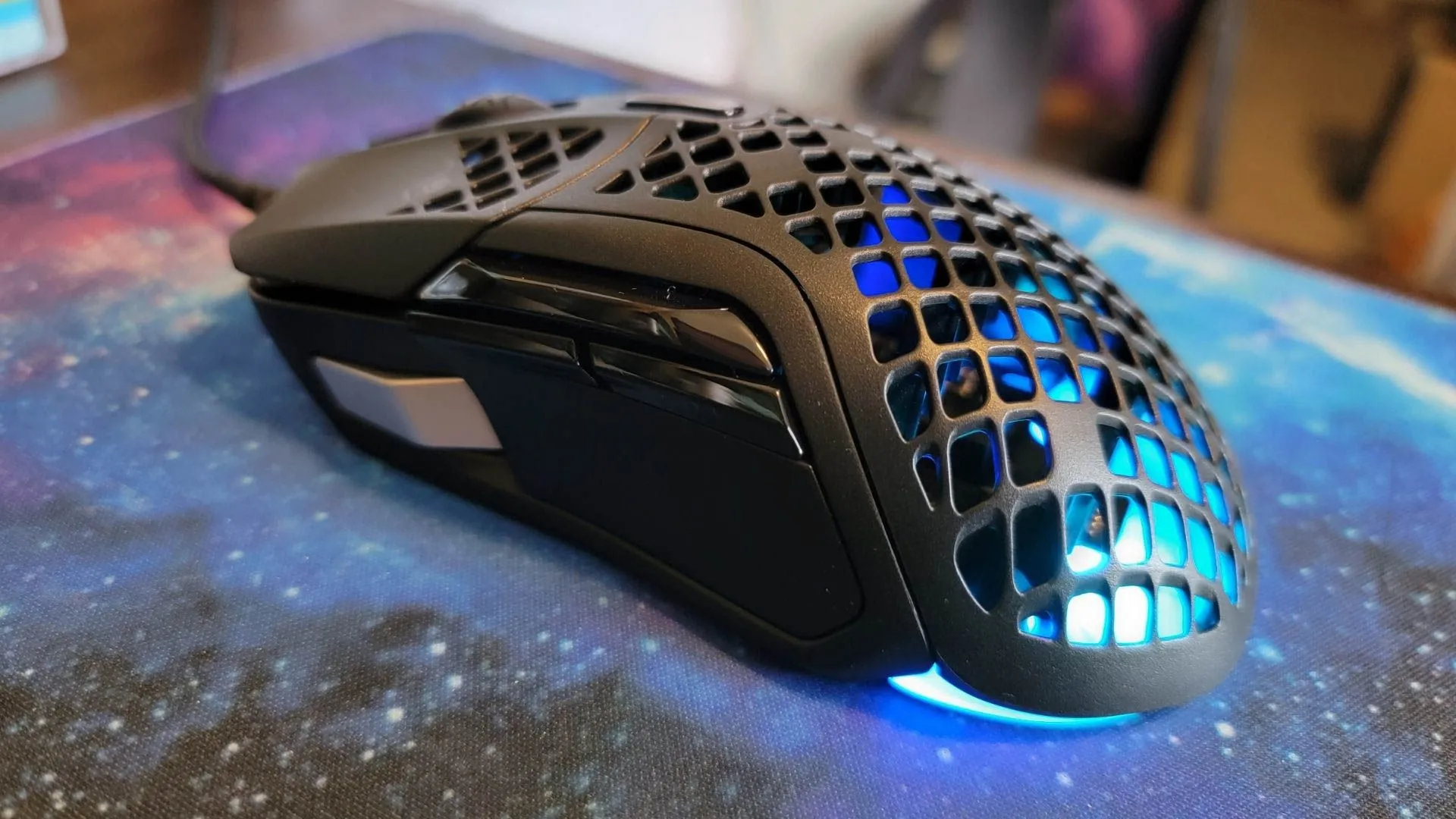 Một con chuột chơi game SteelSeries Aerox 5 với đèn LED xanh, minh họa thiết bị chuột trong ngữ cảnh tìm kiếm con trỏ.