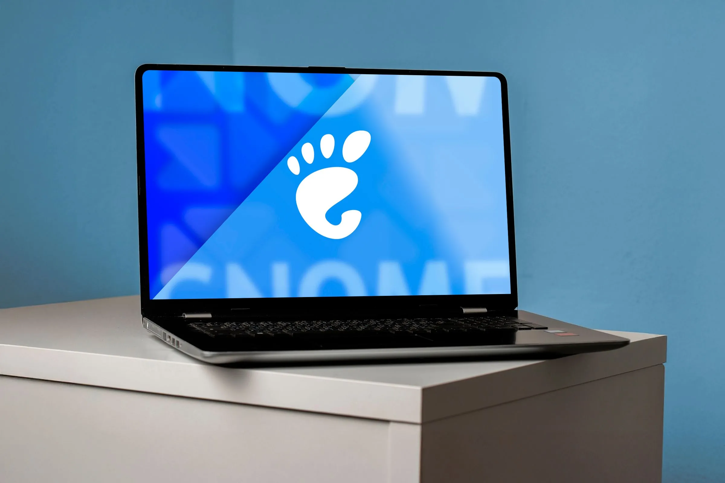 Một máy tính xách tay với màn hình hiển thị logo GNOME và giao diện desktop, minh họa bản cập nhật GNOME 48.