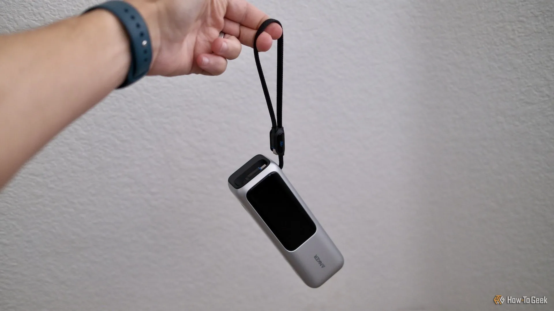 Một người đang cầm sạc dự phòng Anker Power Bank 25K với dây đeo tích hợp, giải pháp sạc di động mạnh mẽ cho các thiết bị công nghệ.
