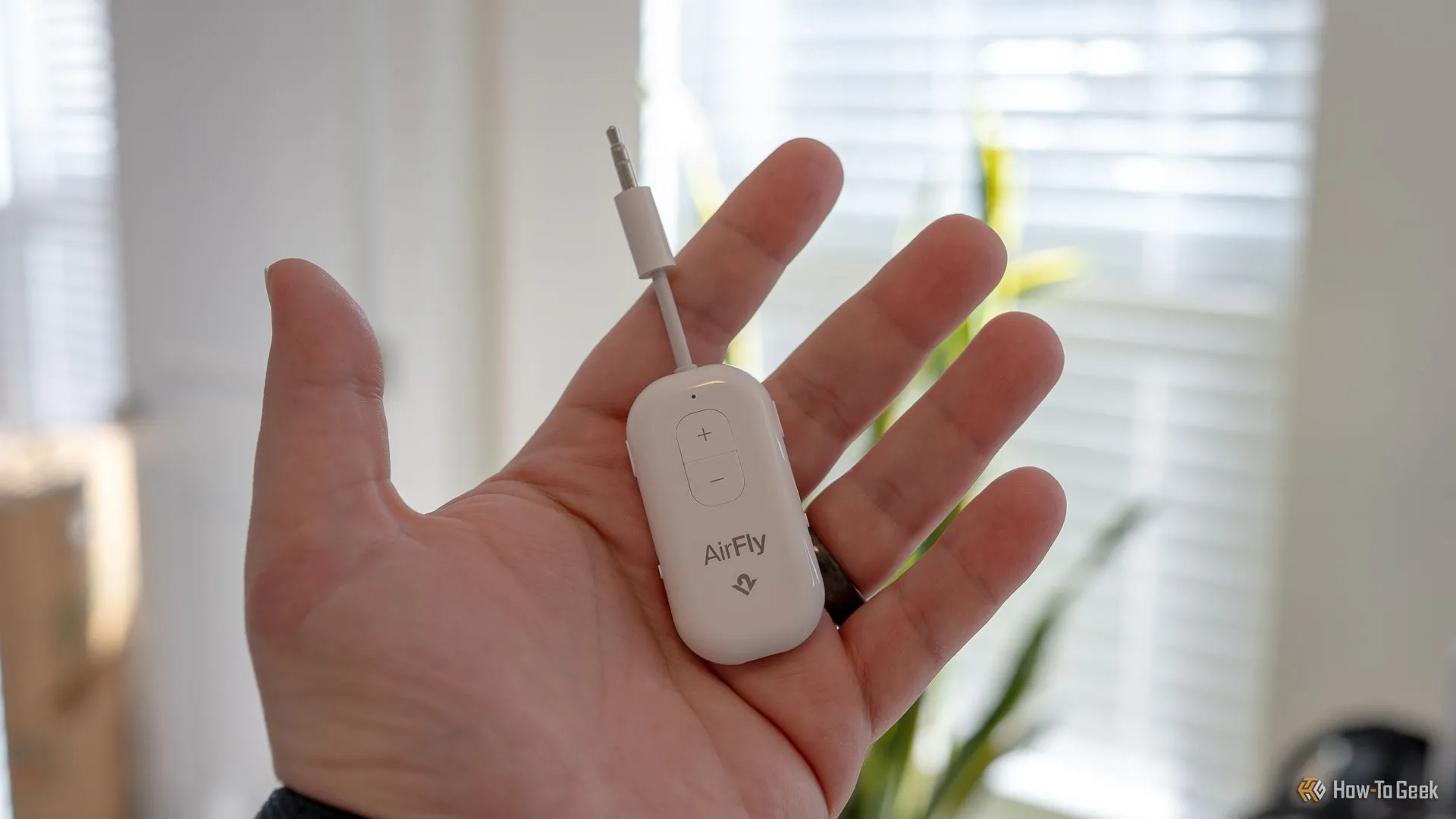 Một người đang cầm thiết bị Twelve South AirFly Pro 2 nhỏ gọn, bộ phát Bluetooth tiện lợi cho giải trí trên máy bay.