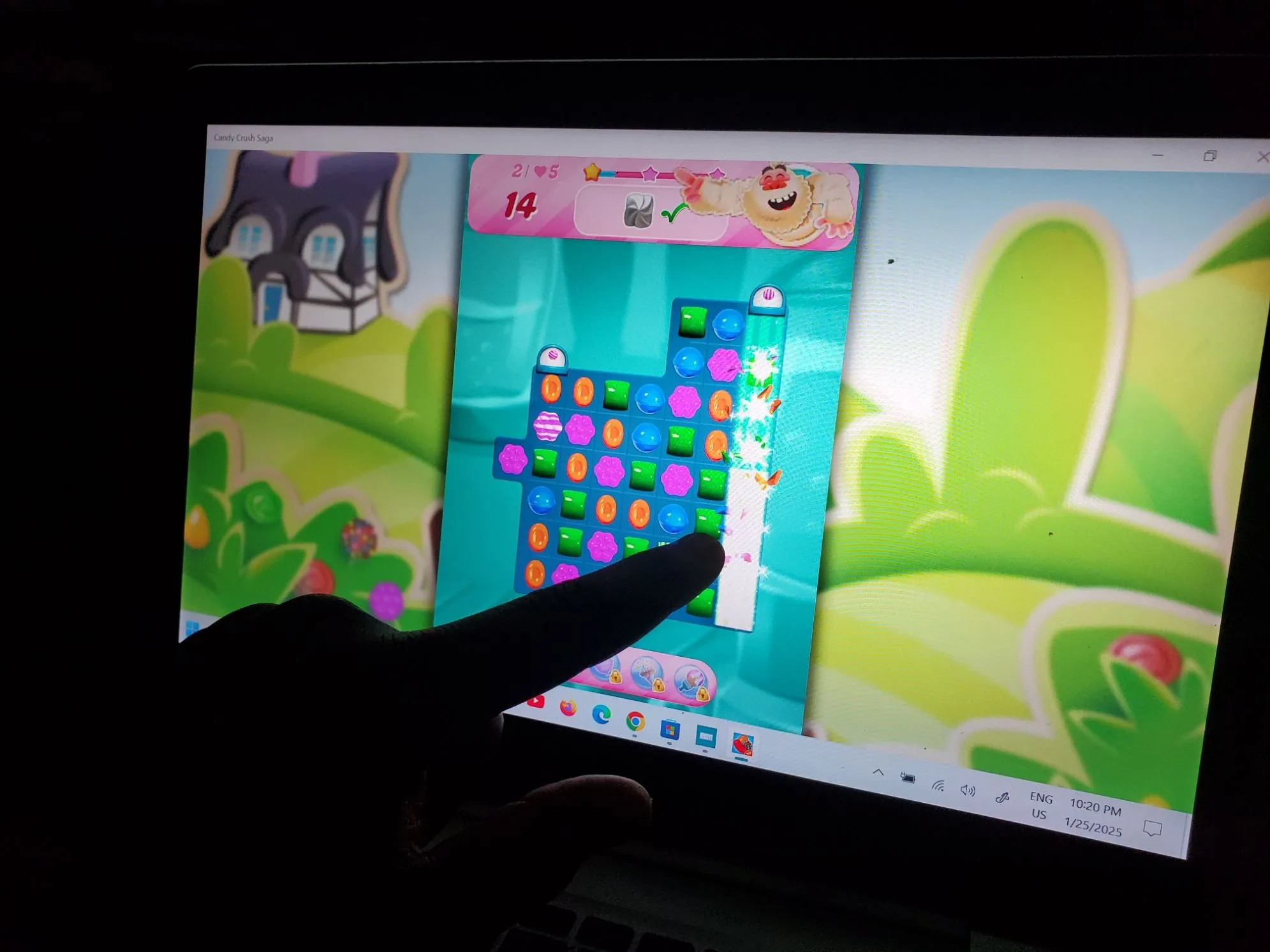 Người đang chơi game Candy Crush trên laptop màn hình cảm ứng