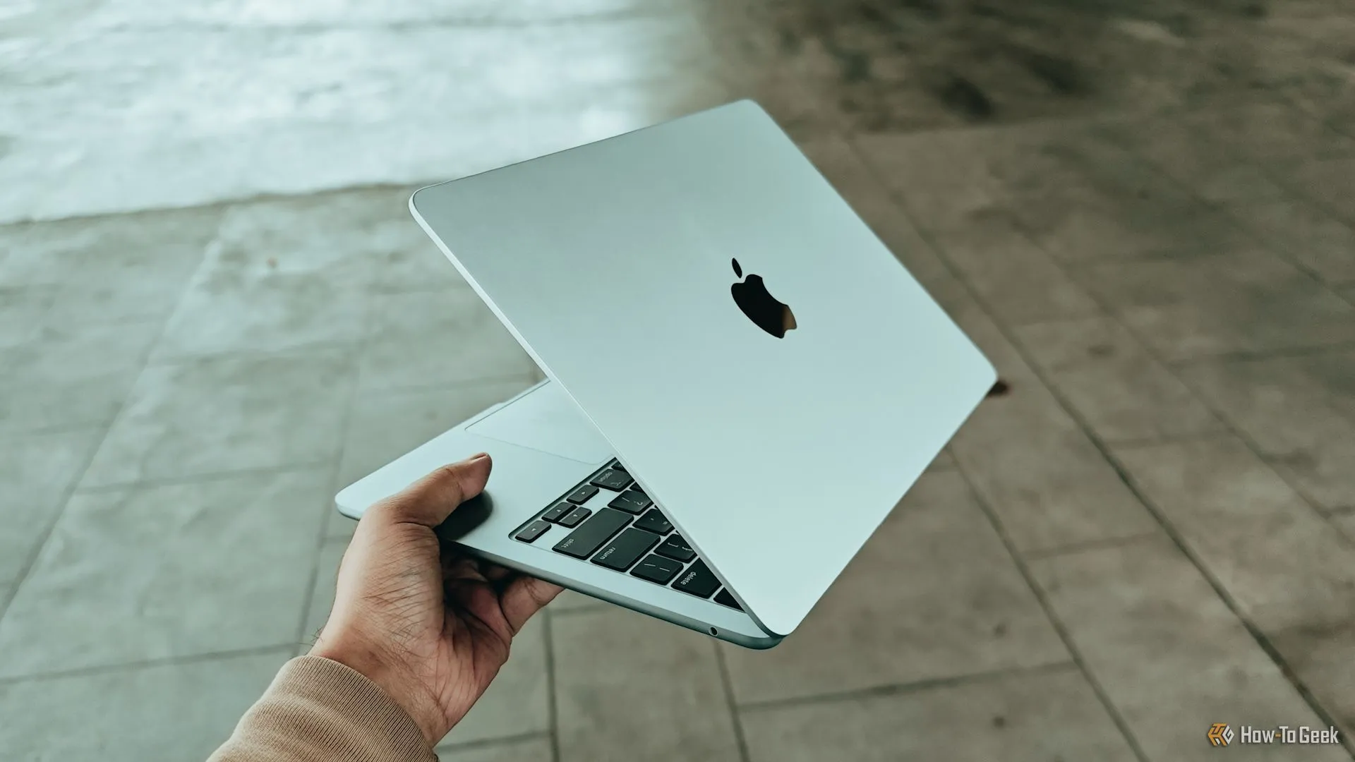 Người dùng cầm MacBook Air M4, hình ảnh tượng trưng cho nhu cầu kết nối di động trên laptop Apple