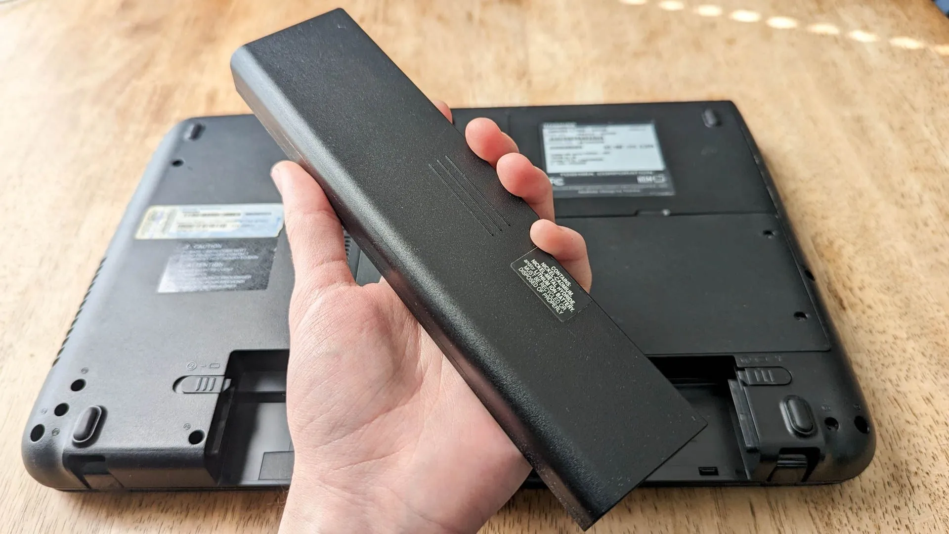 Người dùng đang cầm viên pin laptop có thể tháo rời