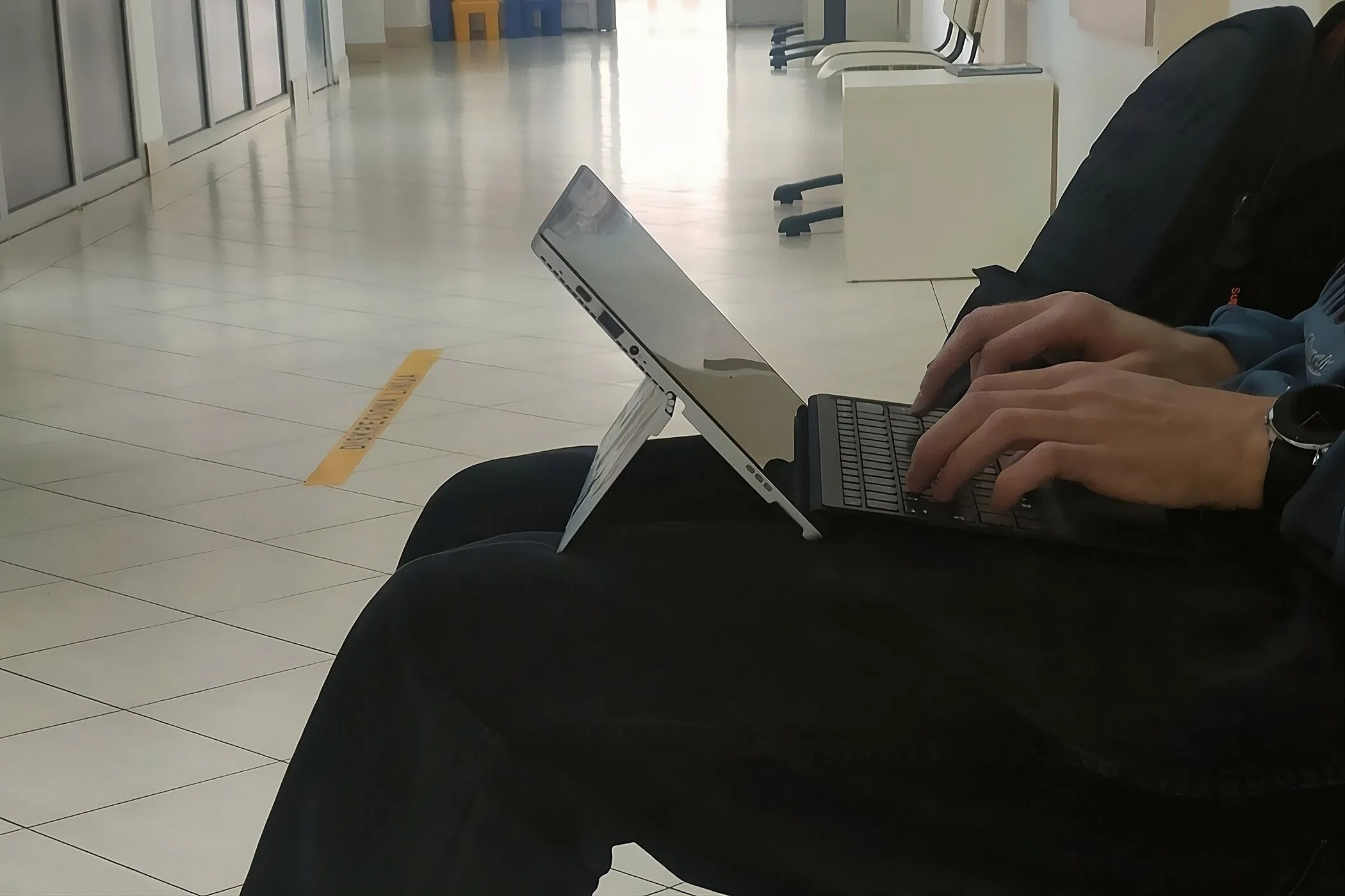 Người dùng đang gõ phím trên laptop 2-in-1 đặt trên đùi