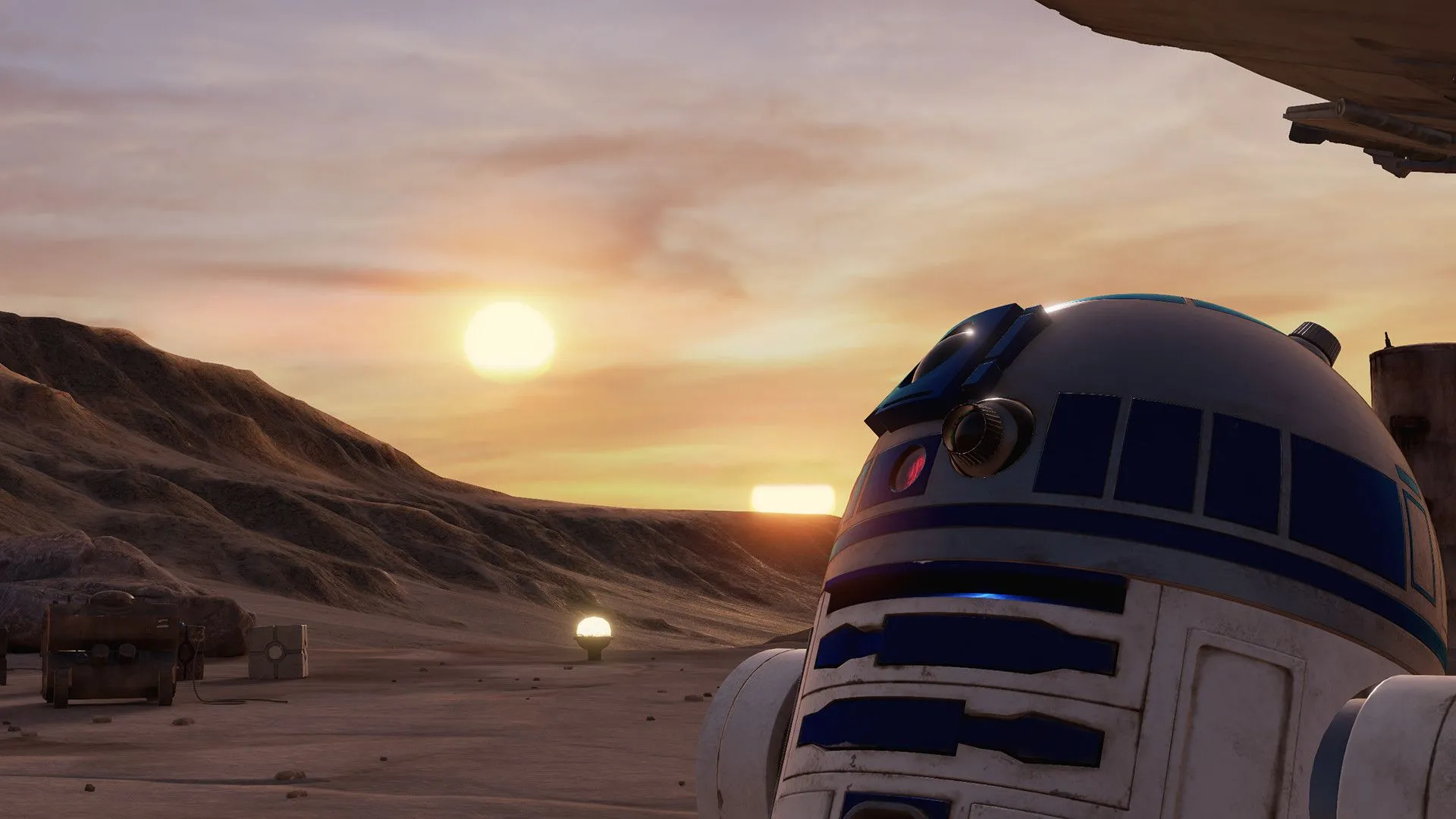 Người máy R2-D2 đứng trên sa mạc với tàu Millennium Falcon và cảnh hoàng hôn phía sau trên hành tinh Tatooine.