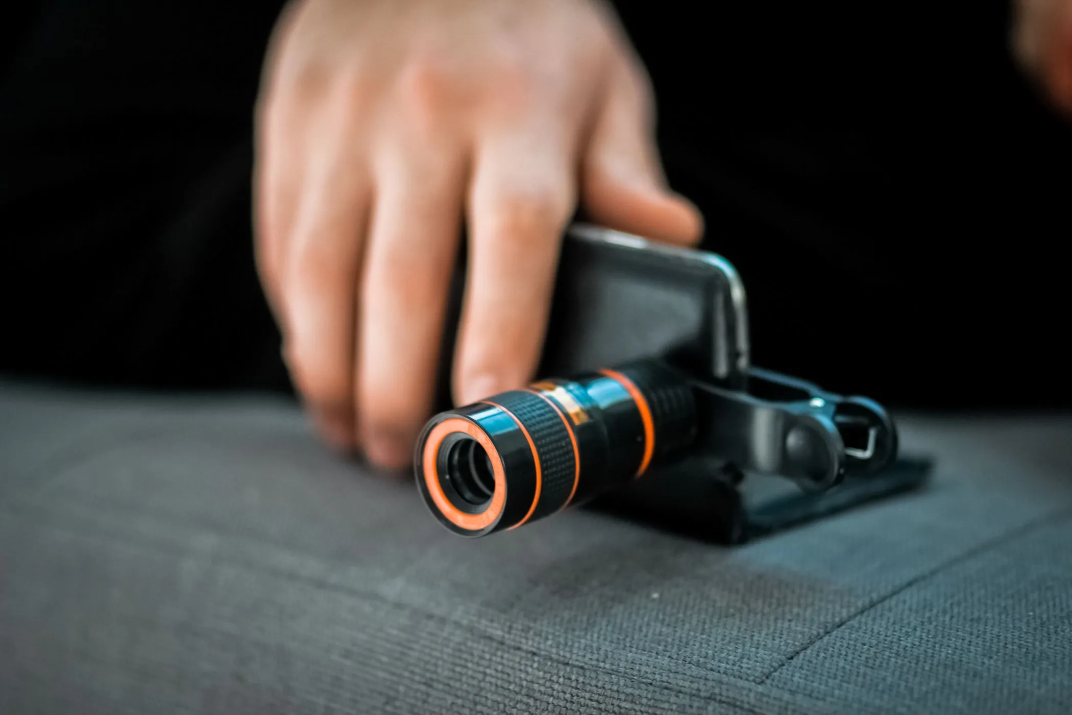 Nhiếp ảnh gia đang sử dụng ống kính zoom quang học gắn ngoài cho điện thoại di động, thể hiện khả năng mở rộng chức năng camera smartphone.