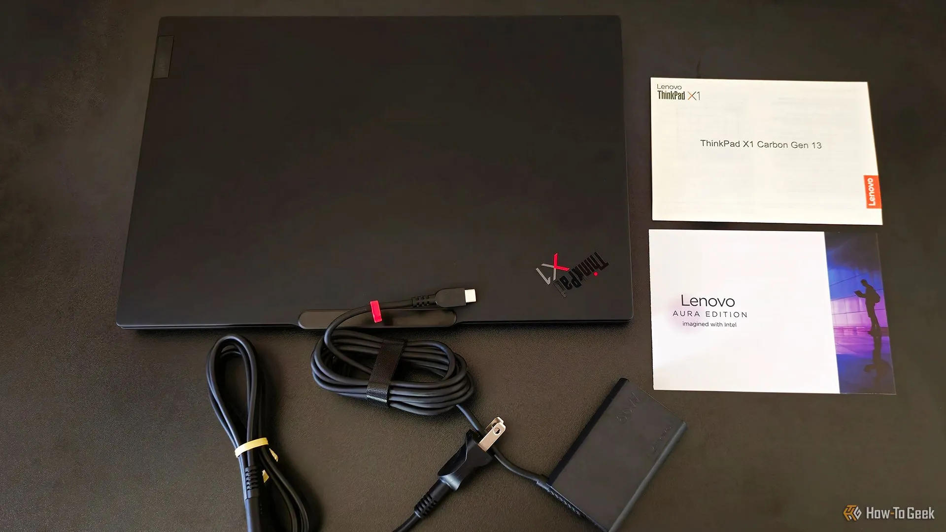 Phụ kiện bên trong hộp đựng của Lenovo ThinkPad X1 Carbon Gen 13 Aura Edition, bao gồm laptop và các tài liệu hướng dẫn