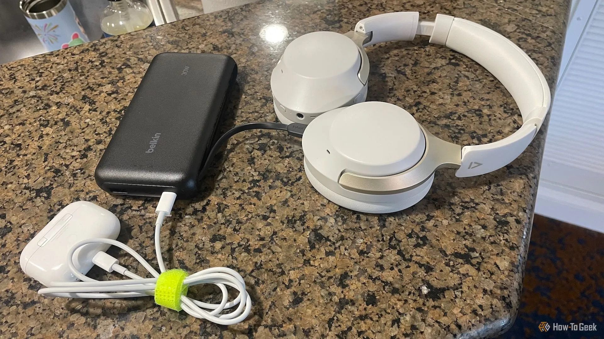 Pin sạc dự phòng Belkin BoostCharge Power Bank 20K đang sạc tai nghe không dây và AirPods, minh họa khả năng sạc đa thiết bị.