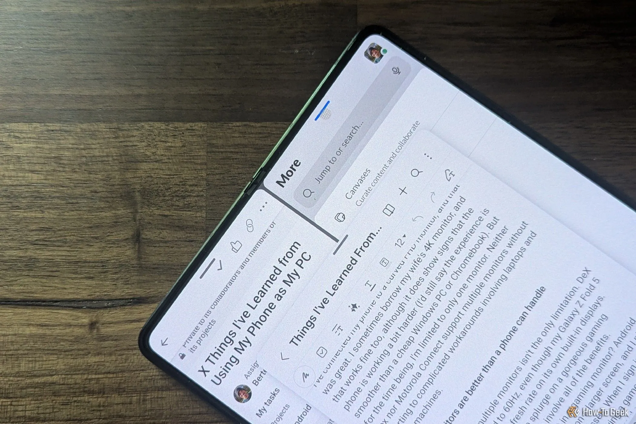 Samsung Galaxy Z Fold 5 màu đen được gập mở, đặt trên bàn làm việc với nhiều ứng dụng đa nhiệm đang chạy trên màn hình.