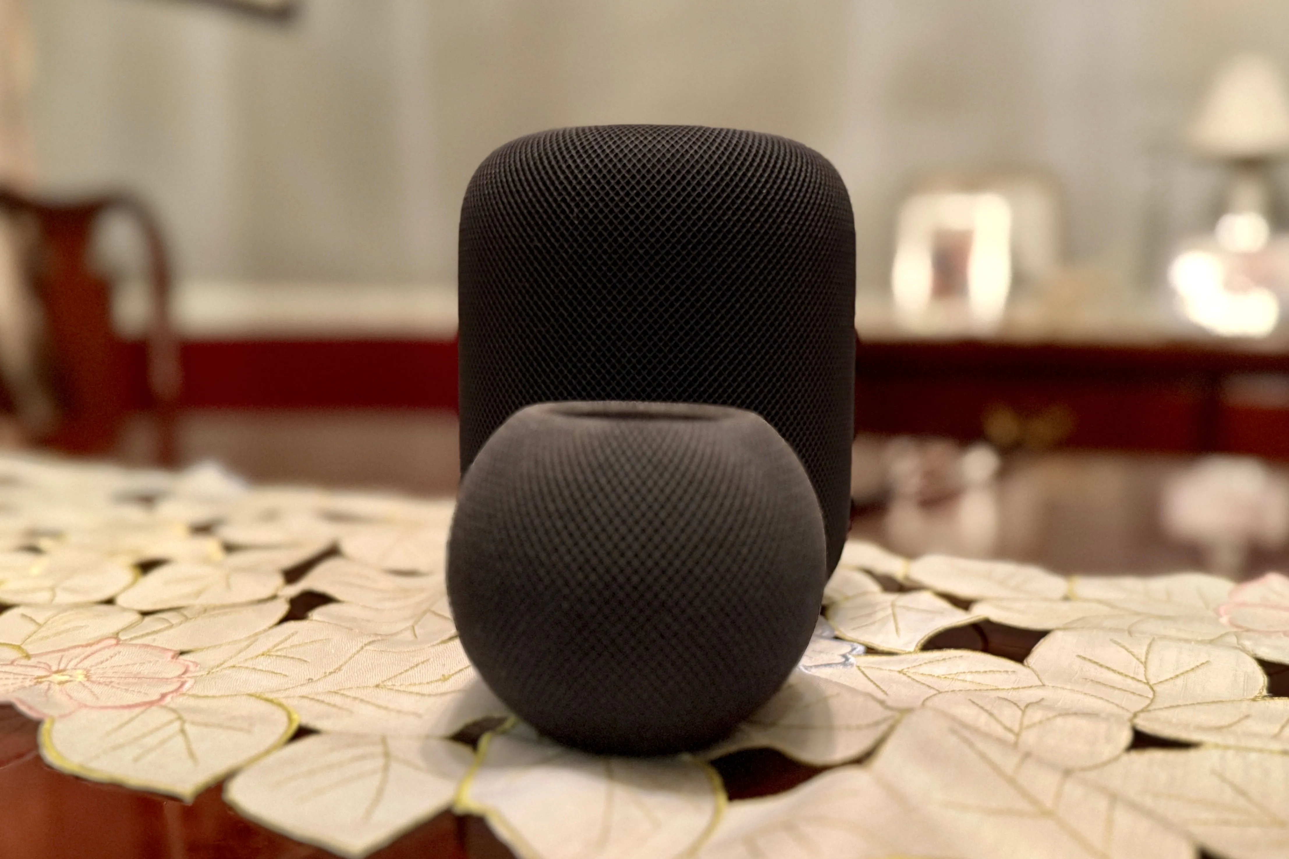 So sánh kích thước HomePod mini (trước) và HomePod (sau), minh họa rõ ràng sự chênh lệch về chiều cao và đường kính.