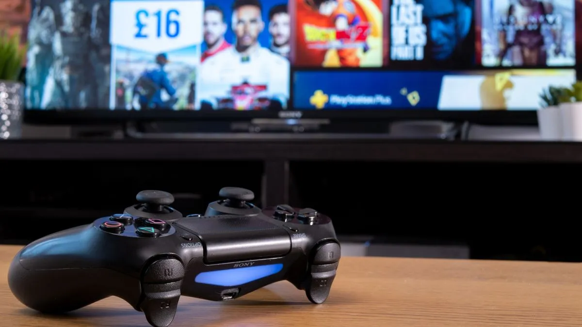 Tay cầm Sony DualShock 4 màu đen đặt trước màn hình TV hiển thị cửa hàng PlayStation Store, minh họa cho trải nghiệm mua và sở hữu game kỹ thuật số trên console.