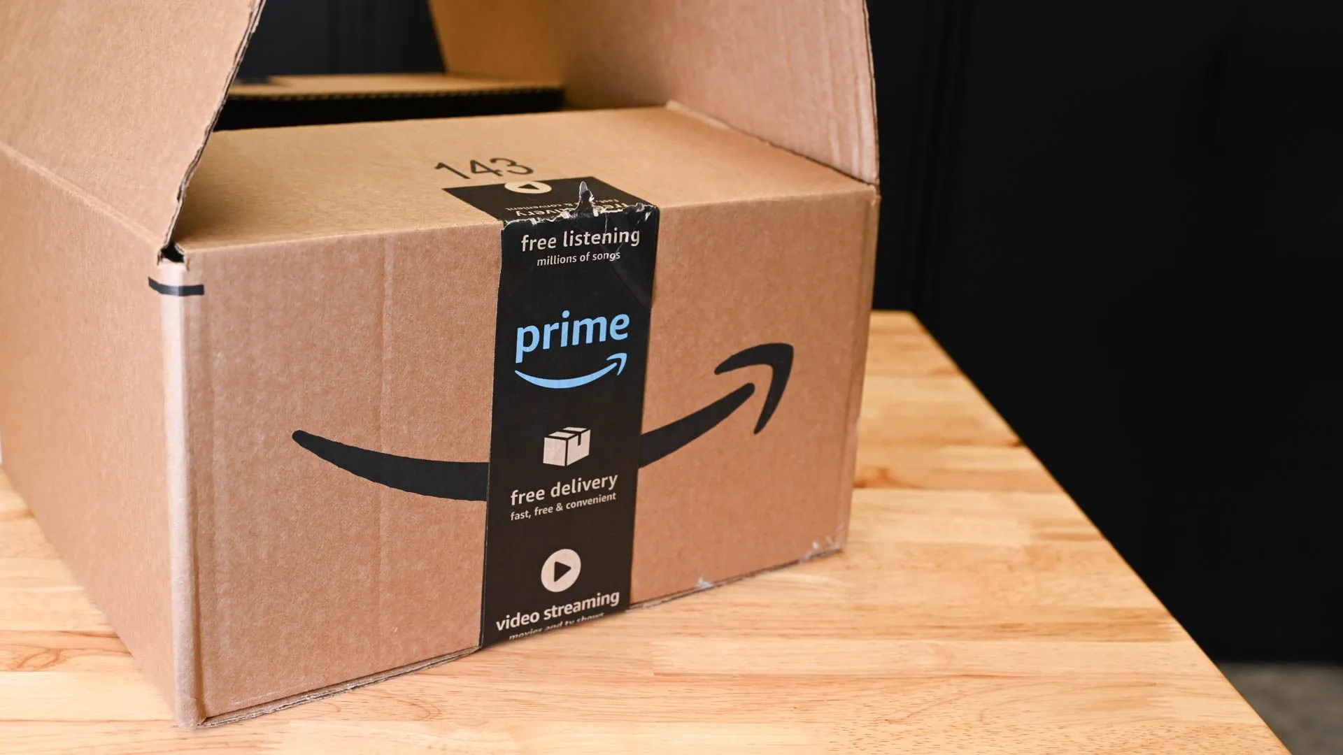 Thùng hàng Amazon trên bàn, biểu tượng cho việc tăng chi phí vận chuyển và thuế quan.