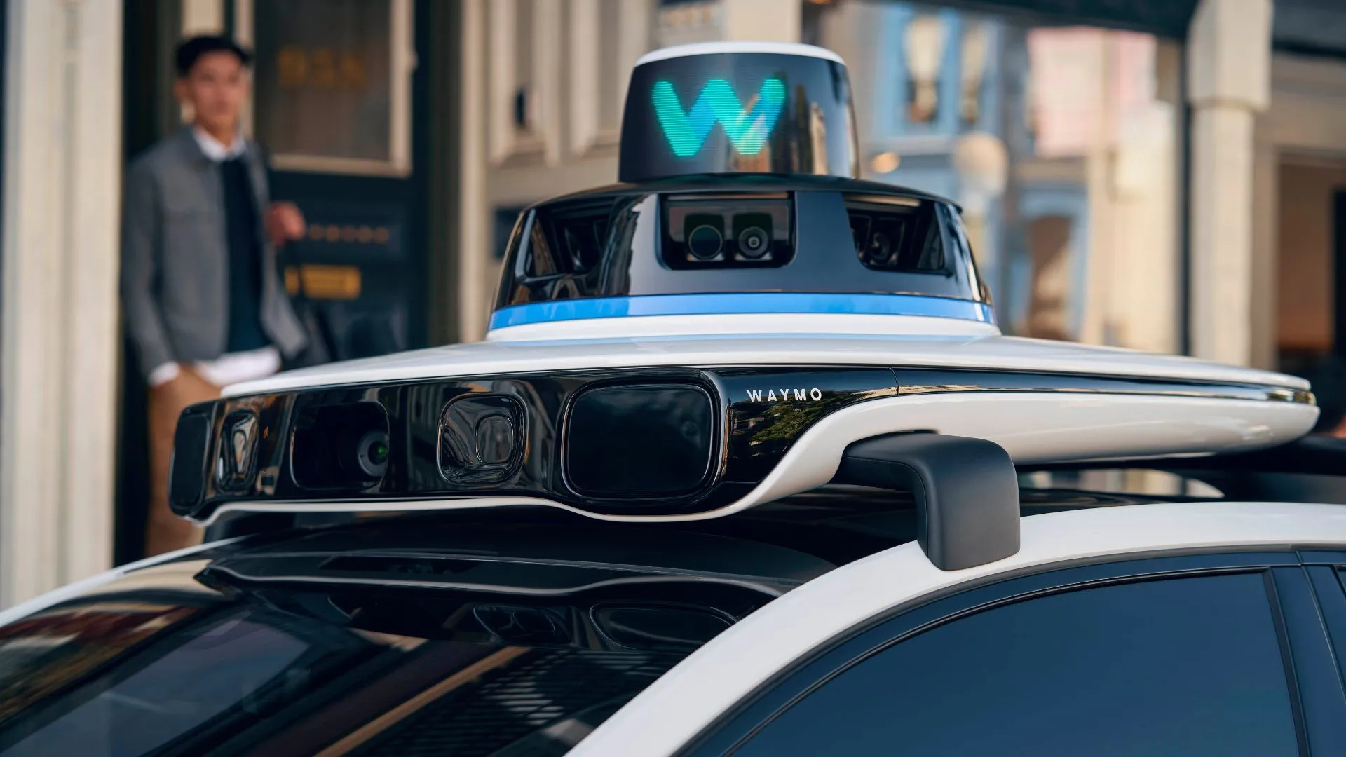 Xe taxi tự lái Waymo Jaguar I-Pace màu trắng với các cảm biến lidar và camera được gắn quanh thân xe, cho thấy công nghệ xe tự hành.