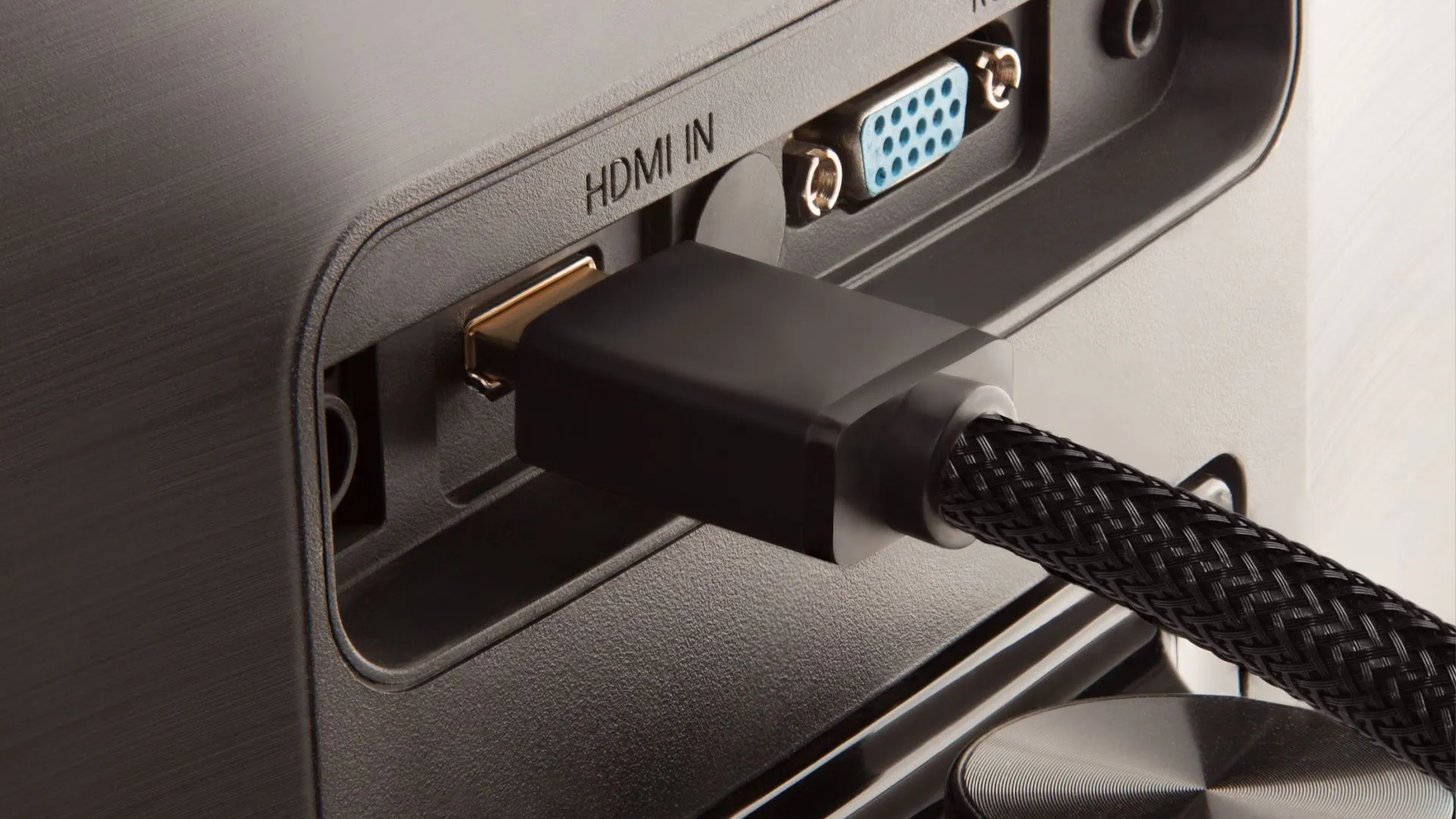 Cáp HDMI được cắm vào phía sau của một màn hình máy tính, đại diện cho một trong những cổng kết nối hiện đại và phổ biến cho trải nghiệm hình ảnh chất lượng cao.