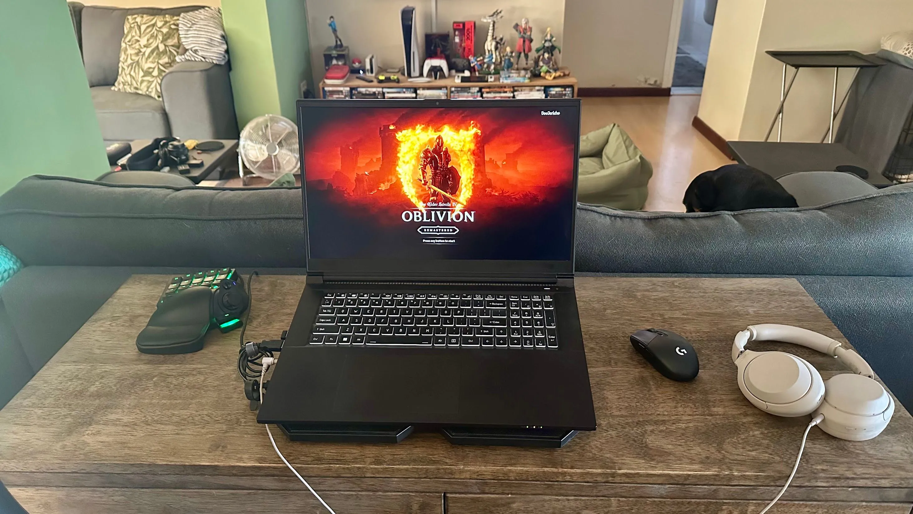 Laptop gaming đặt trên đế tản nhiệt, kèm theo bàn phím một tay Razer Tartarus màu đen ở bên trái, tối ưu công thái học chơi game.