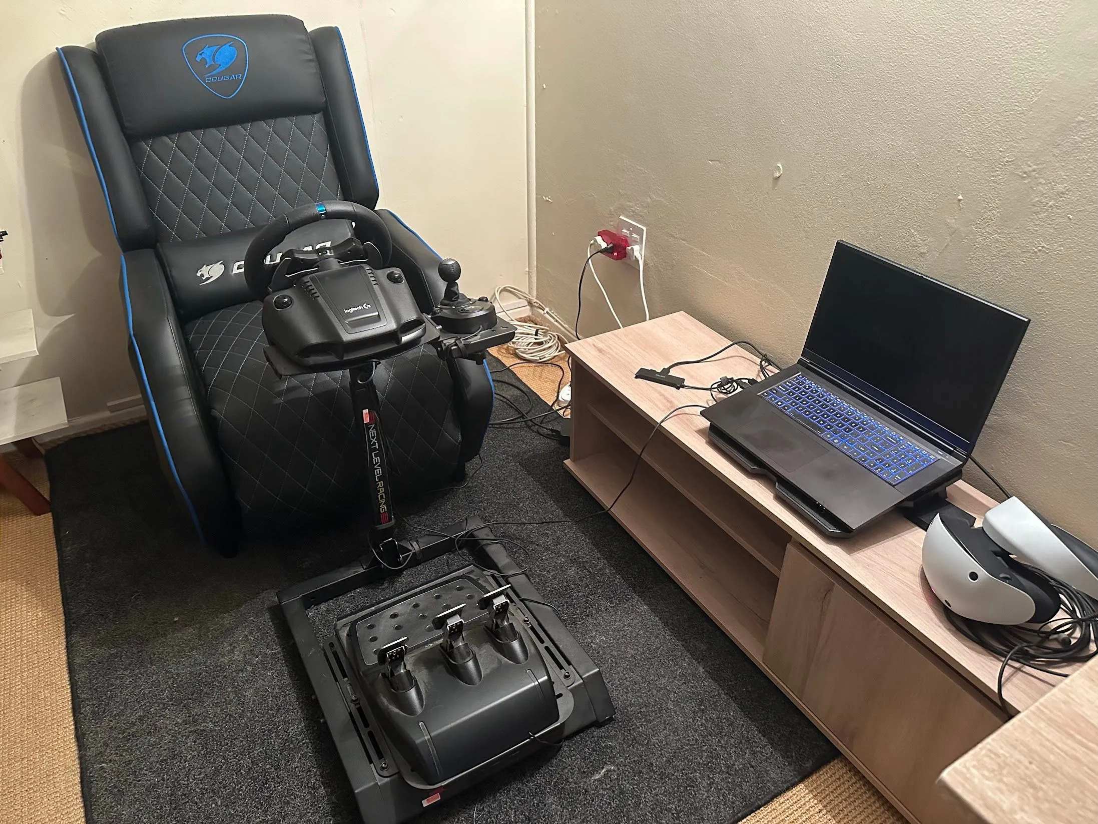 Laptop gaming được đặt cách xa bàn làm việc, gần tai nghe VR và thiết lập vô lăng đua xe, tối ưu không gian và giảm tiếng ồn.