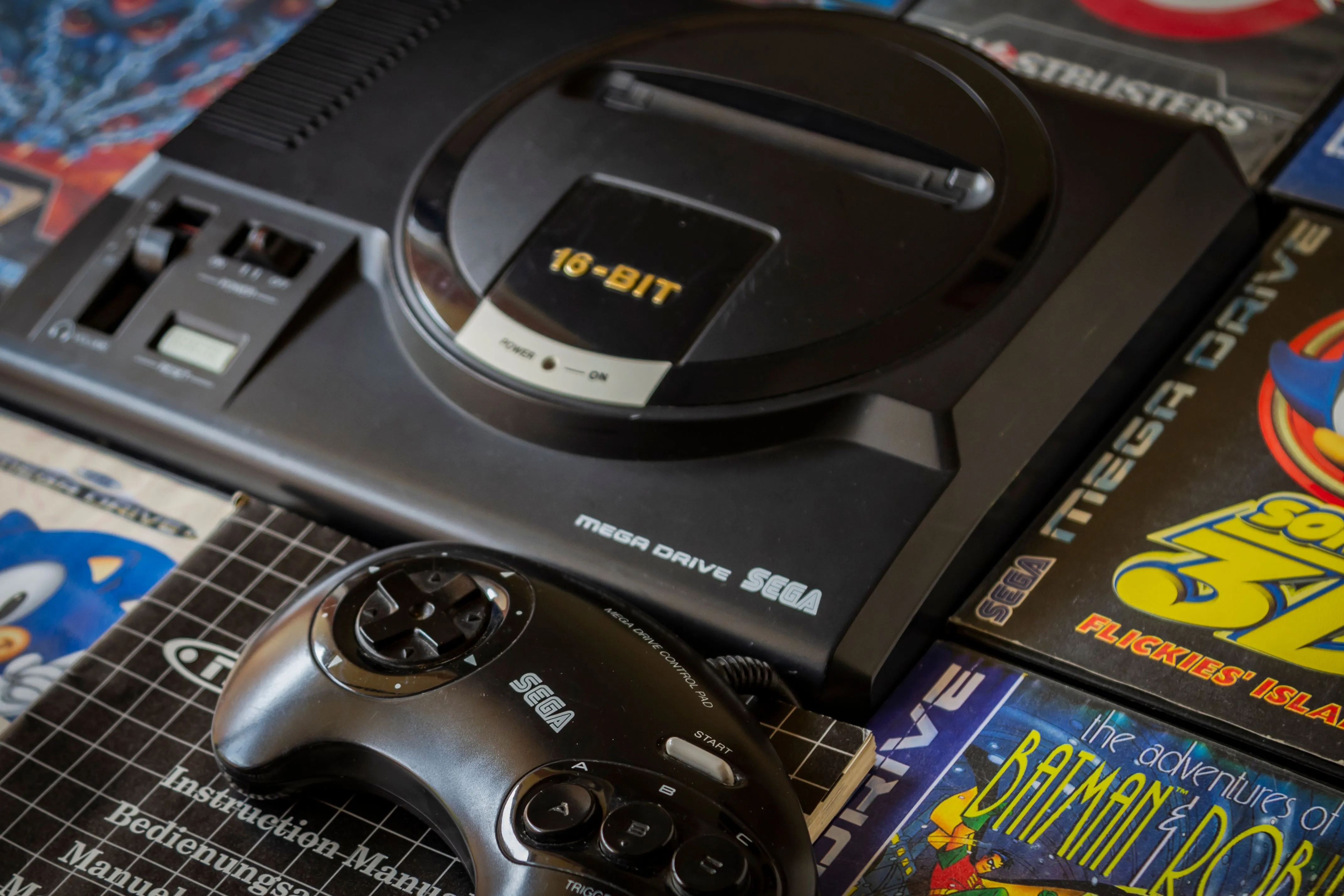 Máy chơi game Sega Genesis cùng một số băng game và tay cầm, biểu tượng của thời đại console wars và công nghệ Blast Processing.