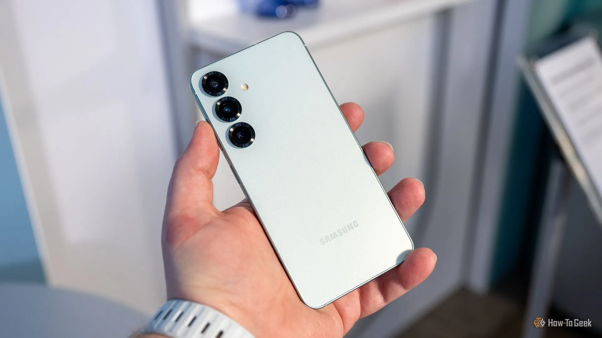 Một người đang cầm điện thoại Samsung Galaxy S25 và quan sát cụm camera sau, làm nổi bật thiết kế và ống kính tele.